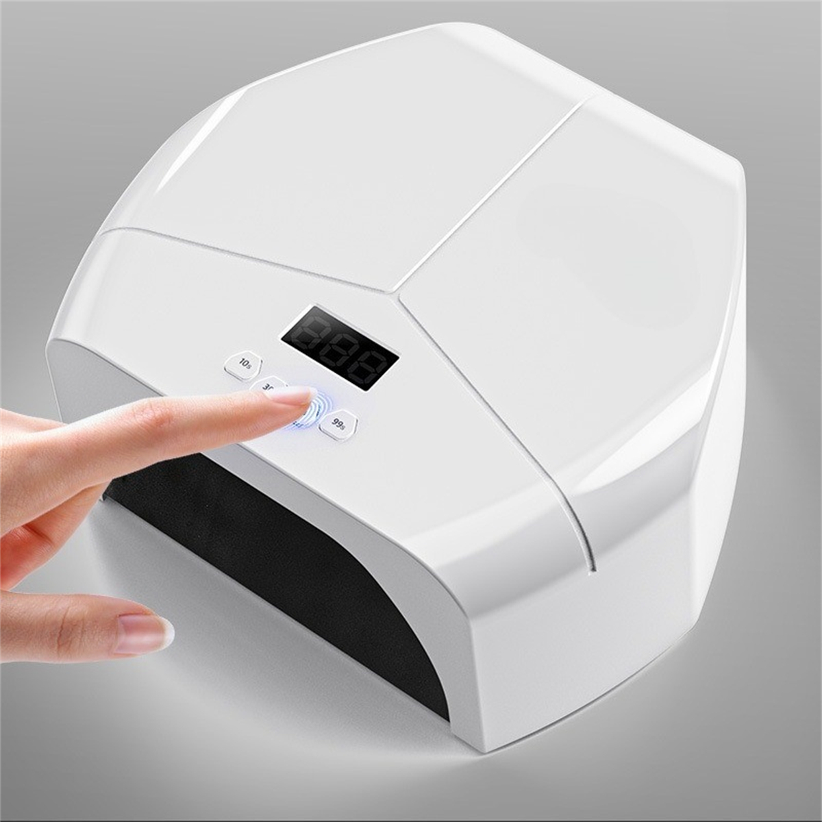 Weißer Nageltrockner mit Digitalanzeige. Ein Finger drückt einen Knopf.