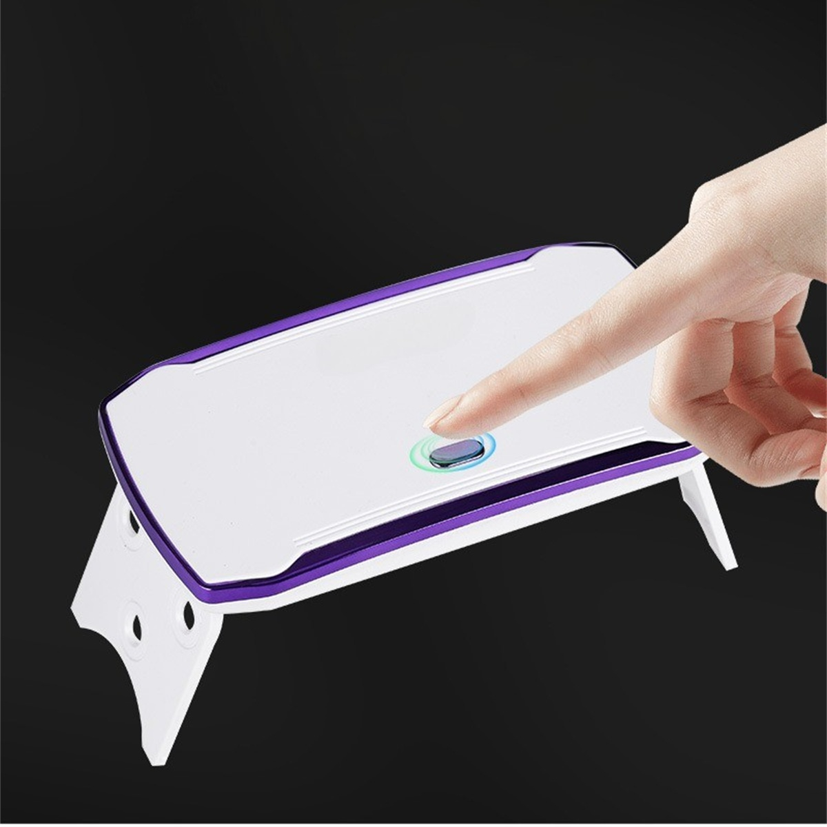 Weiße UV-Nagellampe mit lila Verkleidung, wird von einem Finger berührt. Schwarzer Hintergrund.