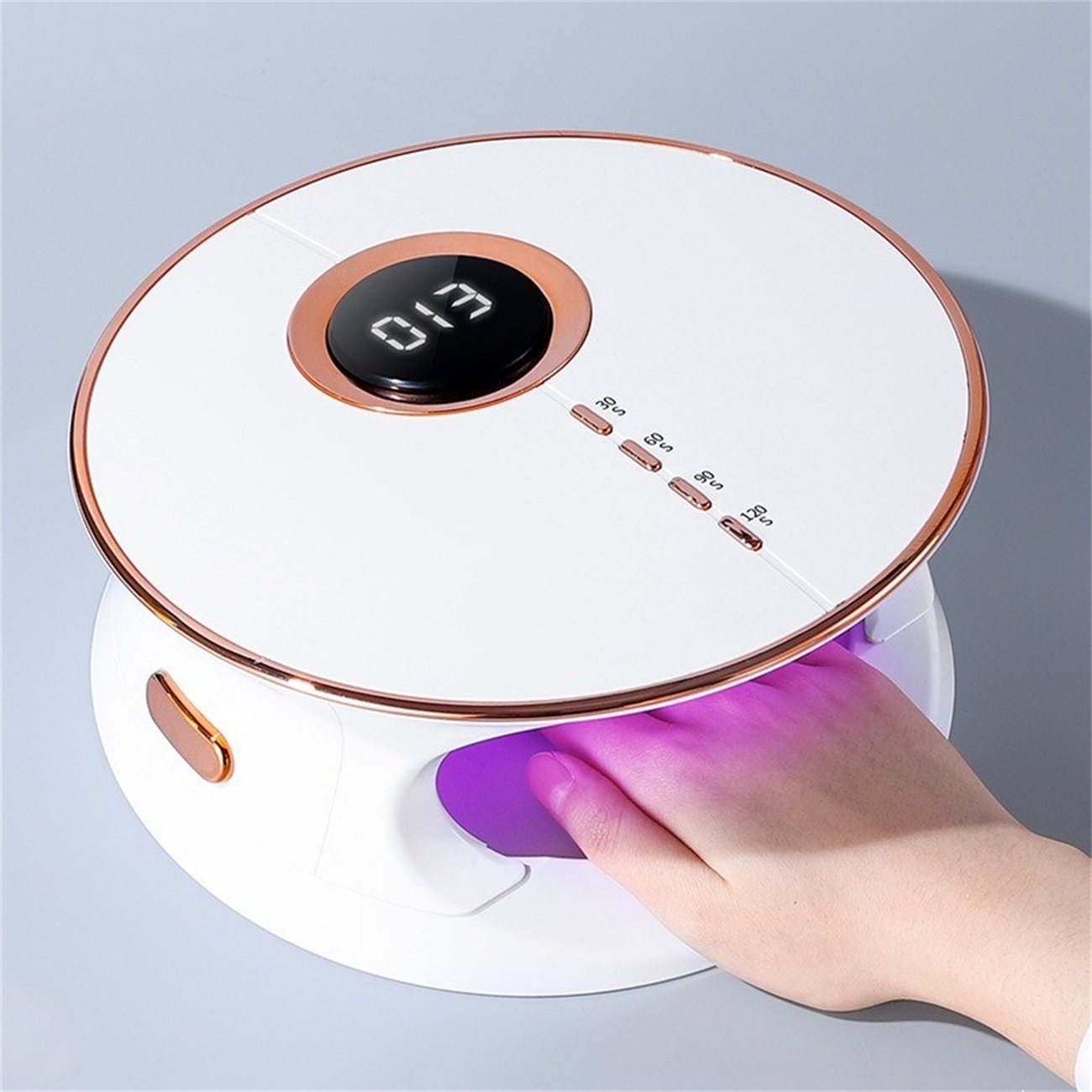 Eine weiße Nagellampe mit Digitalanzeige und Knöpfen. Eine Hand ist darin, das Licht ist an.