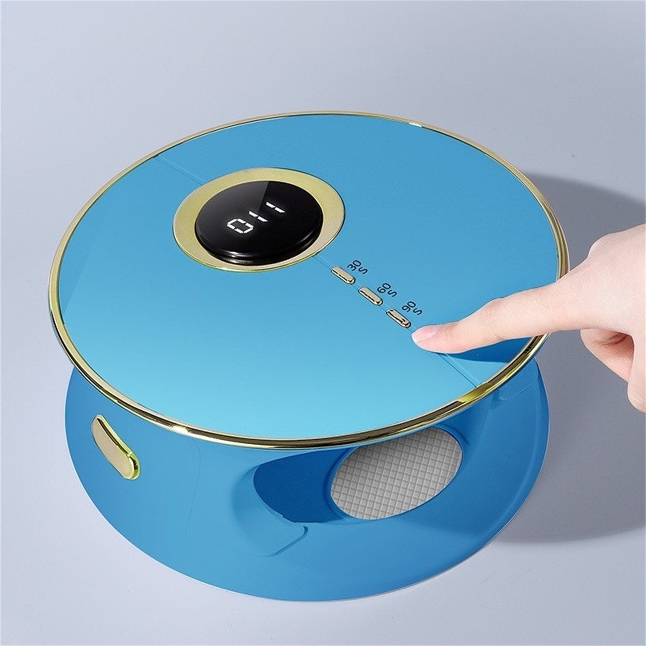 Ein blaues und goldenes Gerät mit Knöpfen und digitaler Anzeige. Eine Hand drückt einen Knopf.