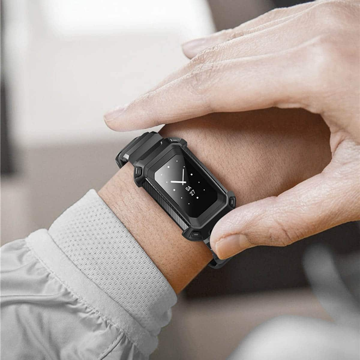 Eine Hand, die eine schwarze Smartwatch mit Bildschirm am Handgelenk trägt. Der Hintergrund ist unscharf.