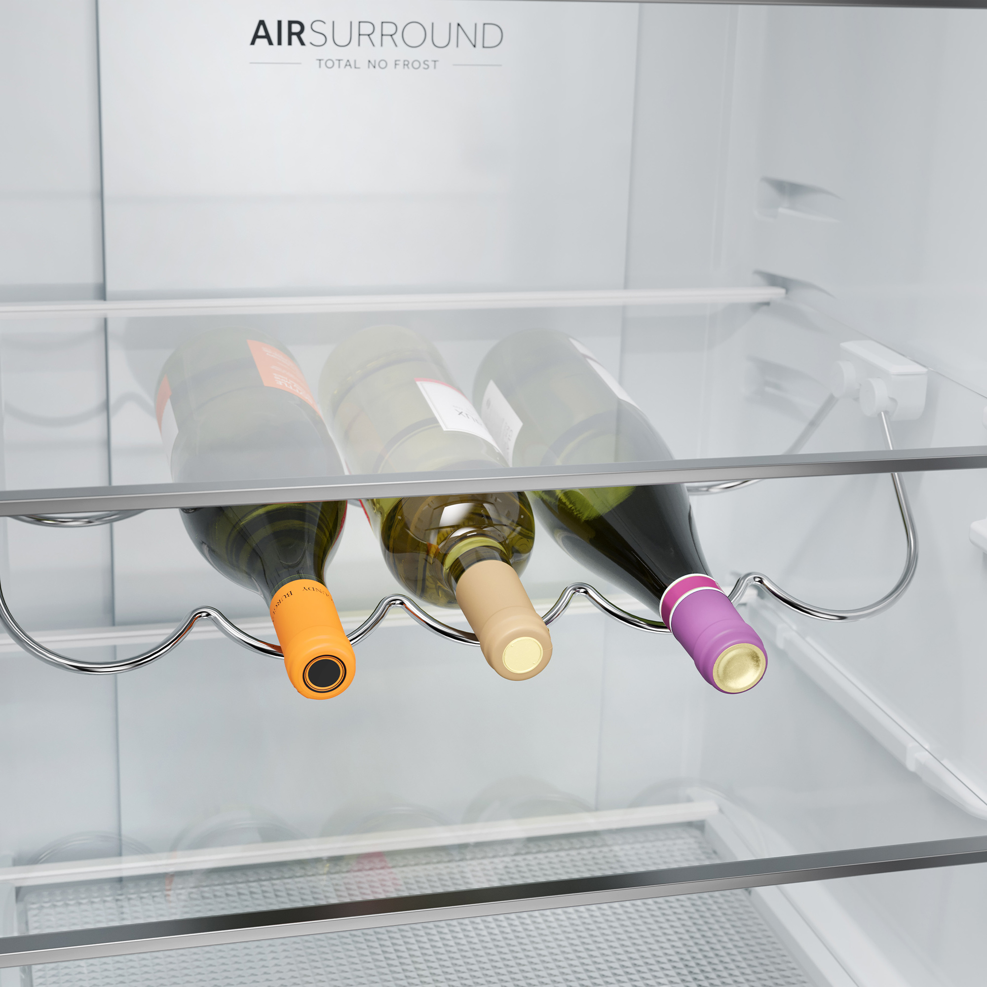 Tre bottiglie di vino in frigo, tenute da un portabottiglie cromato.
