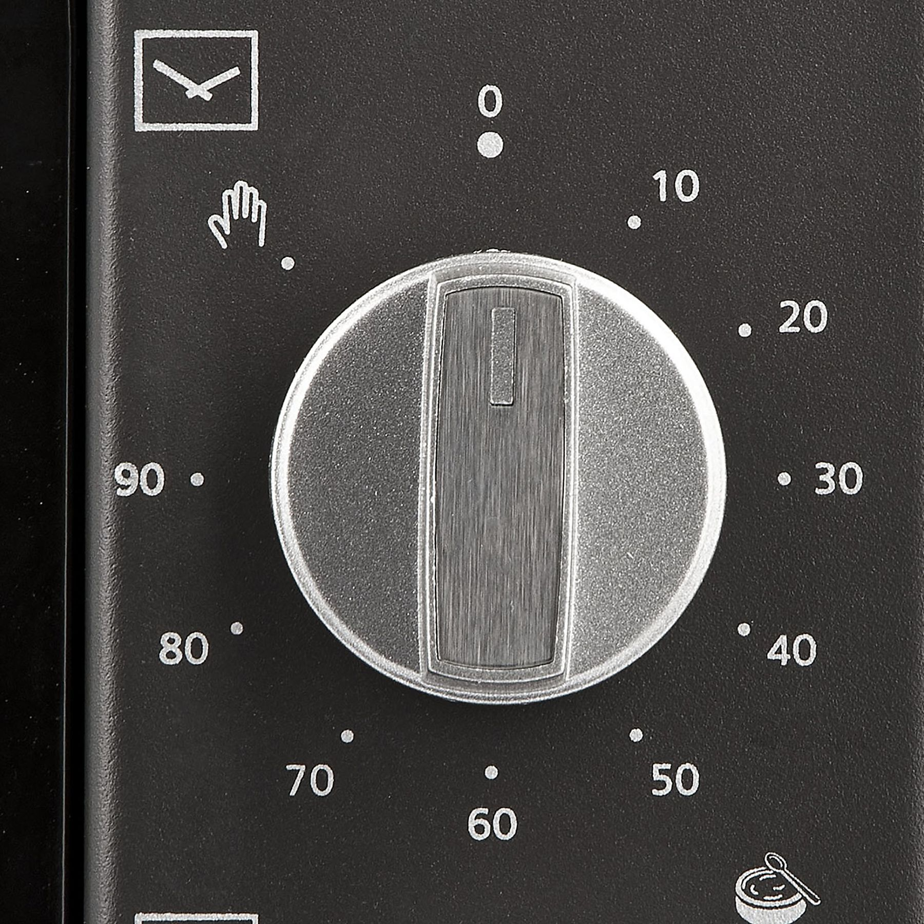 Primer plano de un panel de control de horno con un dial y números. Fondo negro, dial plateado.