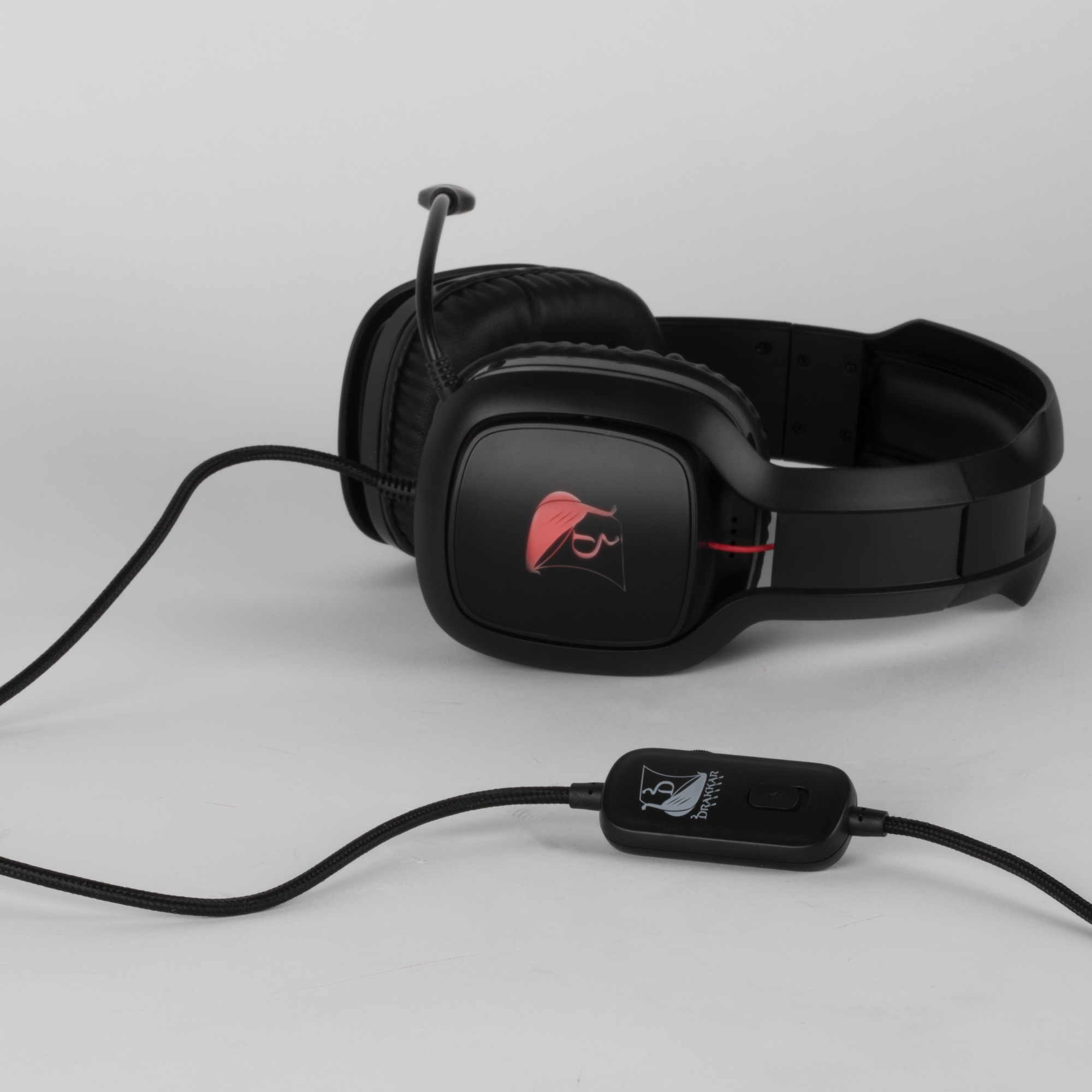 Cuffie da gaming nere con microfono, su una superficie bianca.