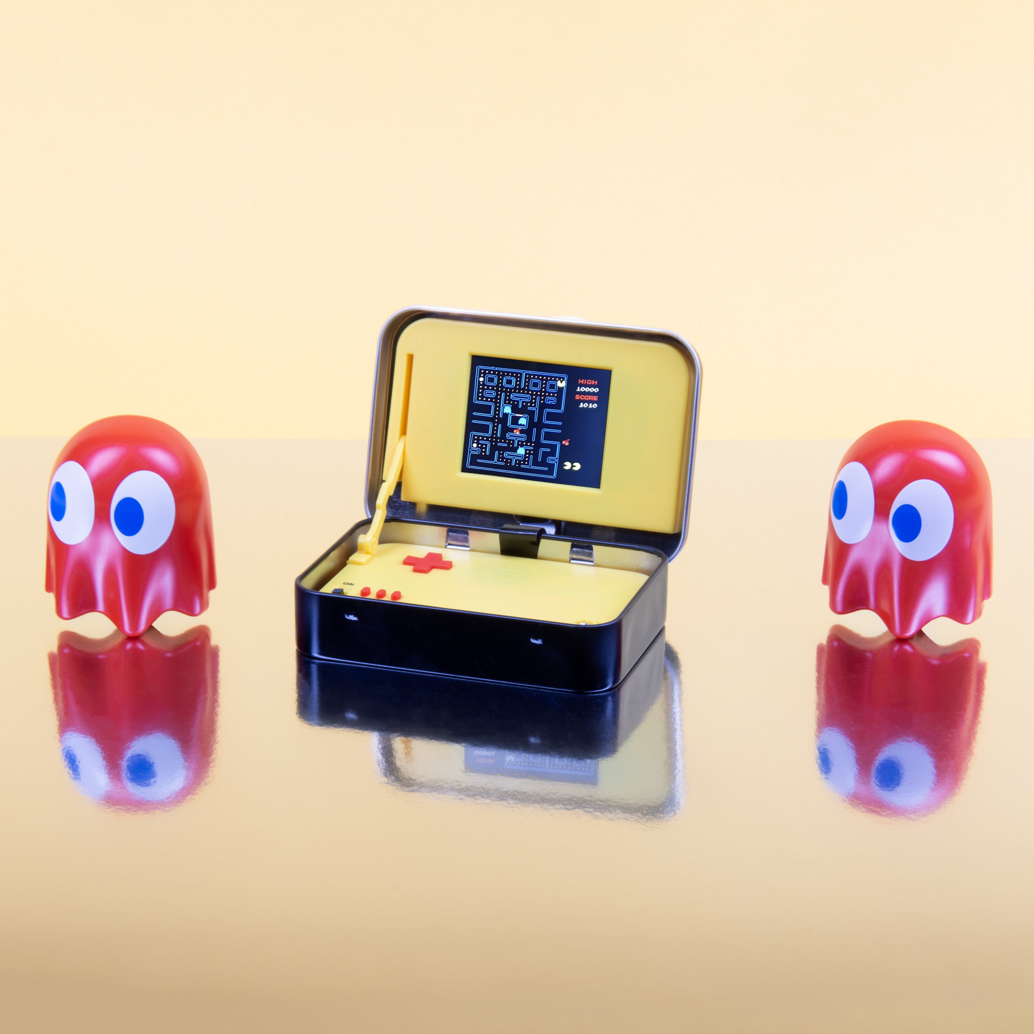 Un gioco arcade di Pac-Man con due figure di fantasmi. Il gioco è in un contenitore giallo.