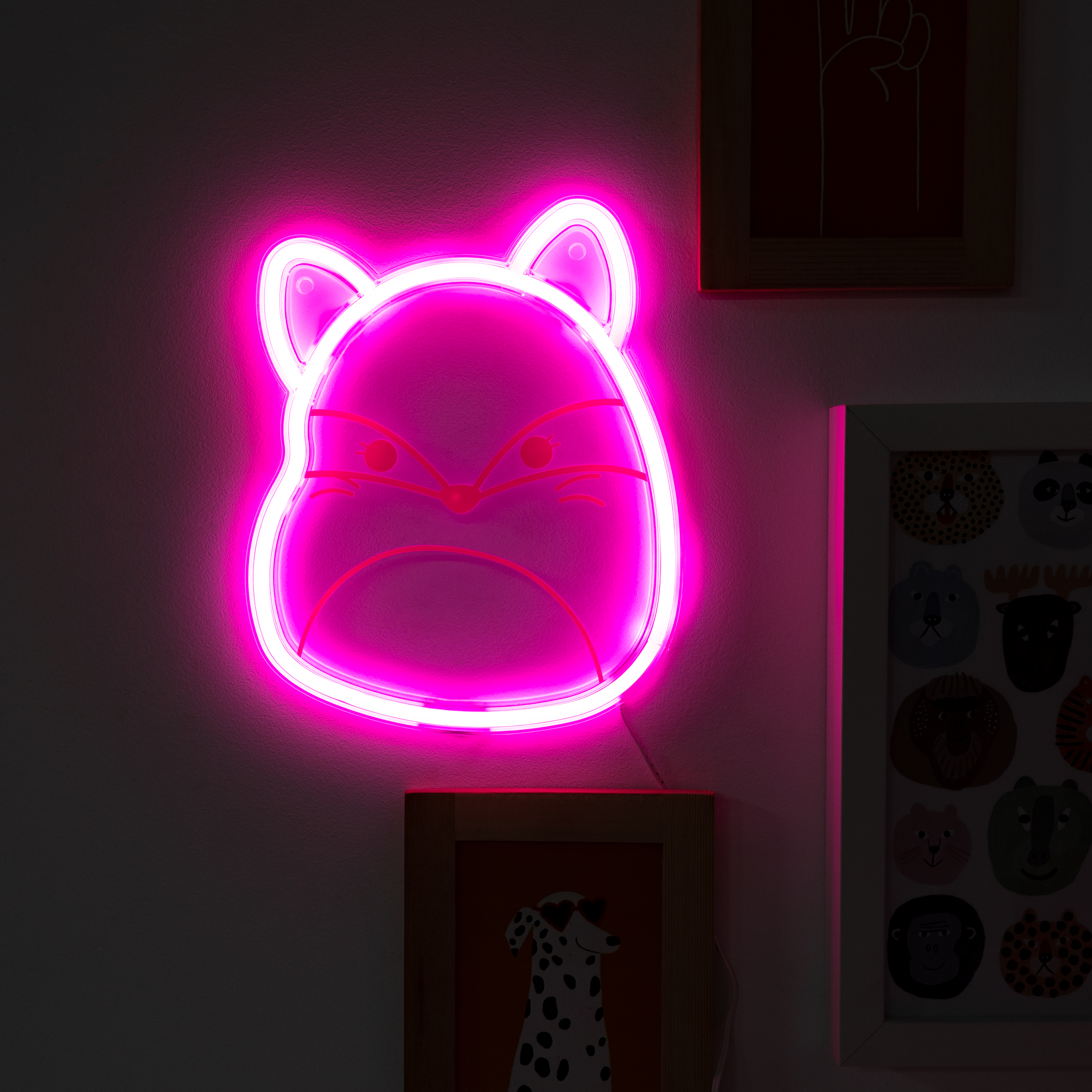 Neonroze vossenkop licht. Omgeven door een roze gloed. Hangt aan een donkere muur.