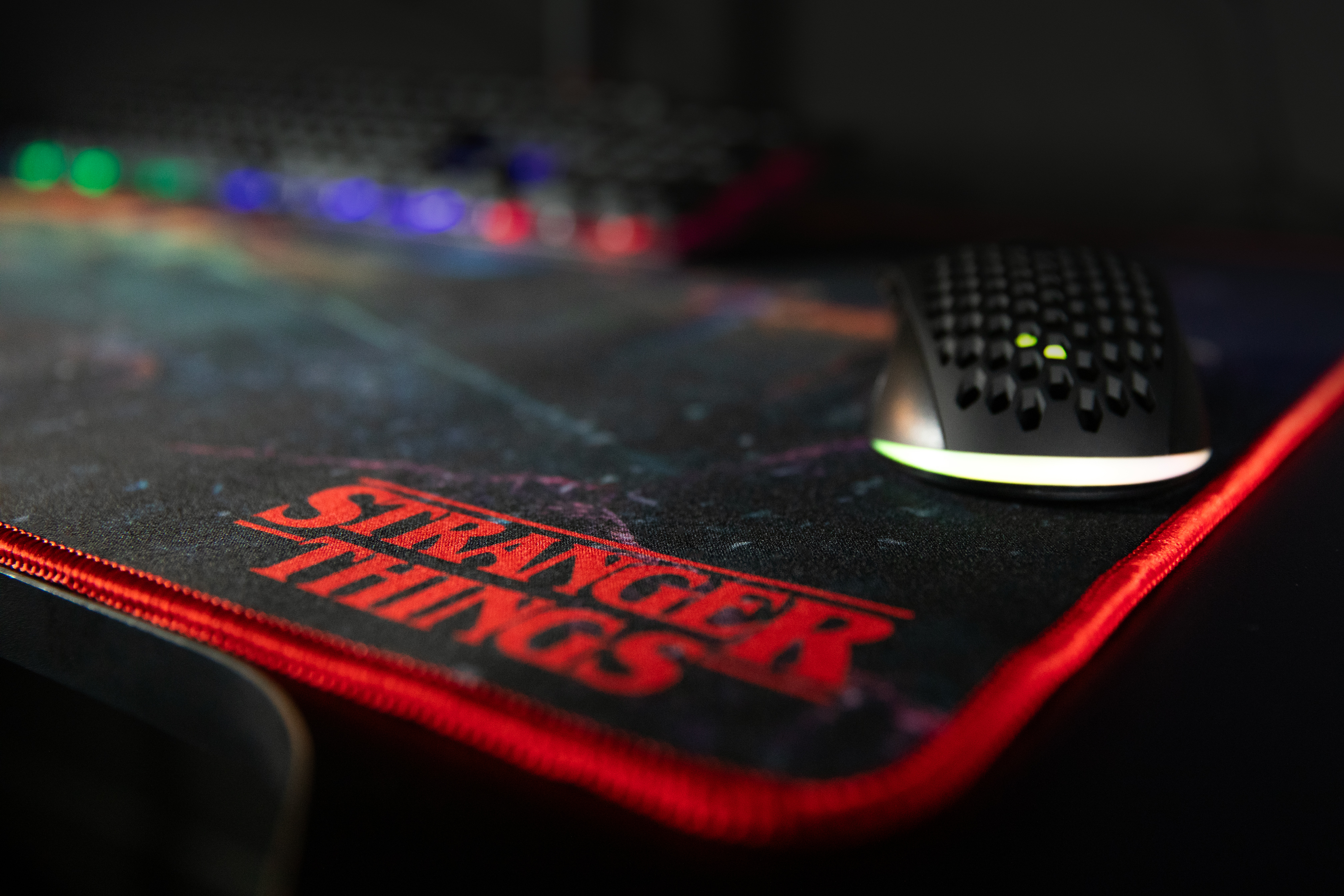 Podkładka pod mysz Stranger Things z czarną myszką. Podkładka ma czerwoną obwódkę i logo.
