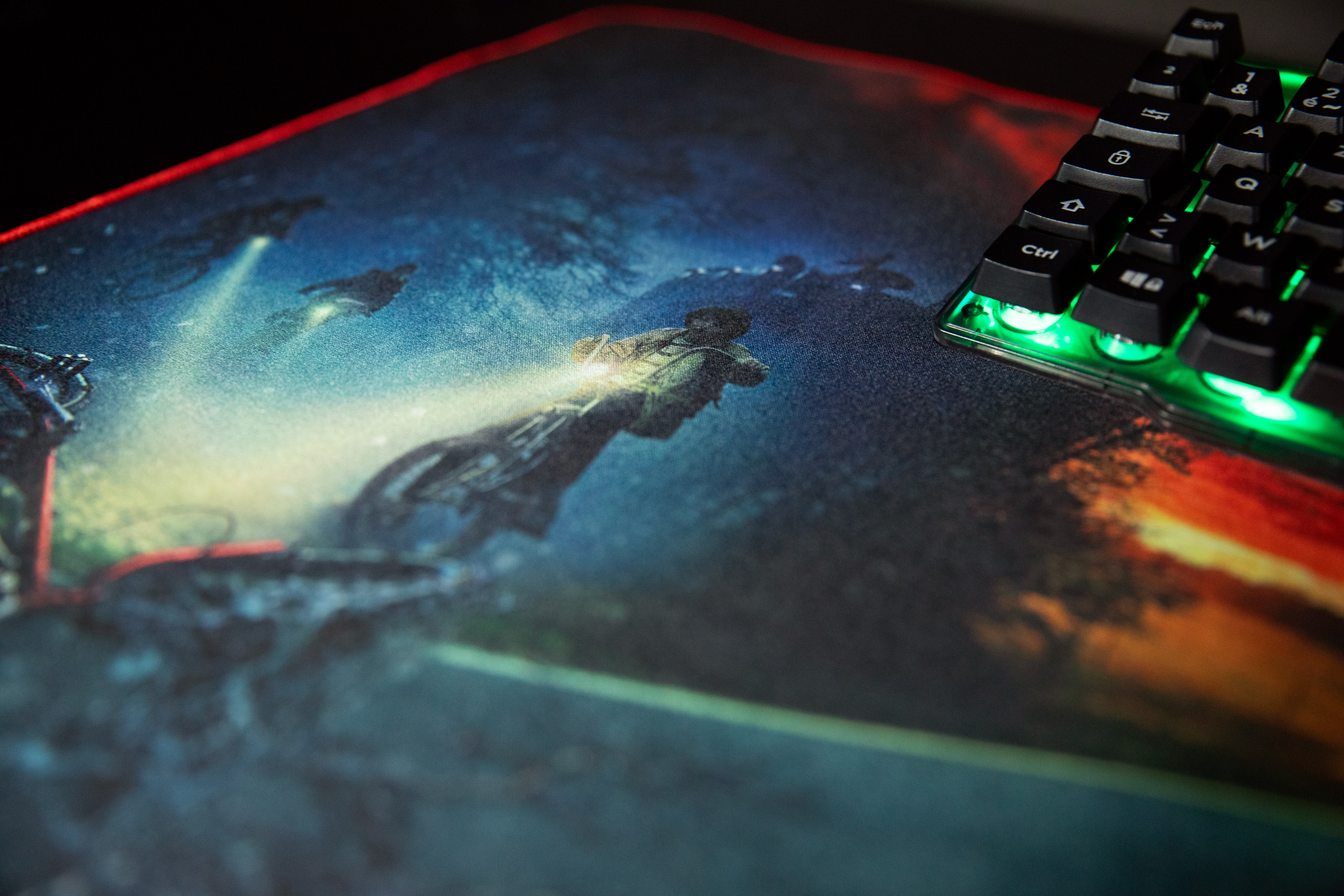 Podkładka pod mysz ze sceną z Stranger Things. Czarna klawiatura w rogu i czerwone światło.