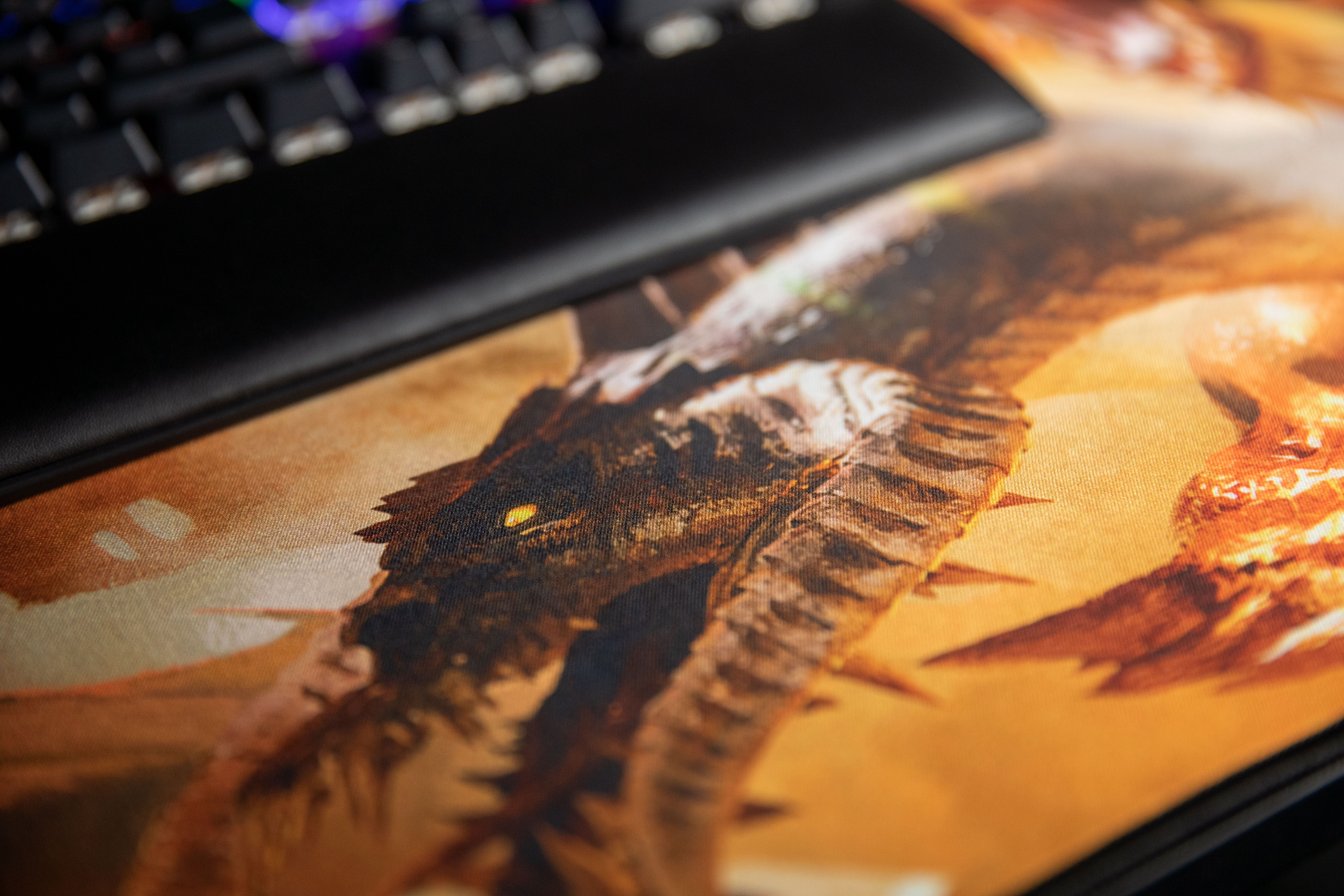 Zbliżenie podkładki pod mysz z motywem smoka z klawiaturą w tle.