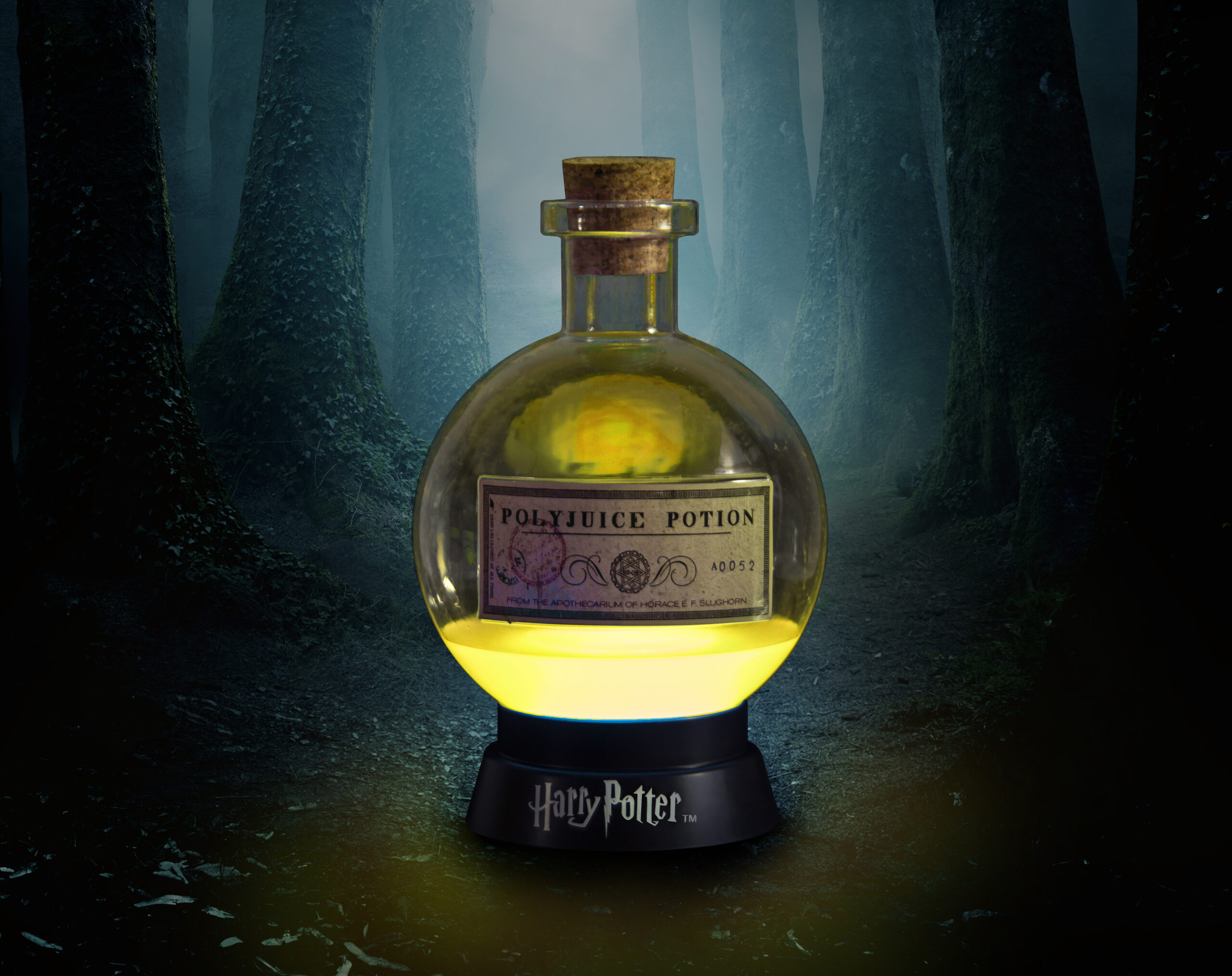 Harry Potter Felix Felicis fles van onderen verlicht. Op zwarte standaard met bos achtergrond.