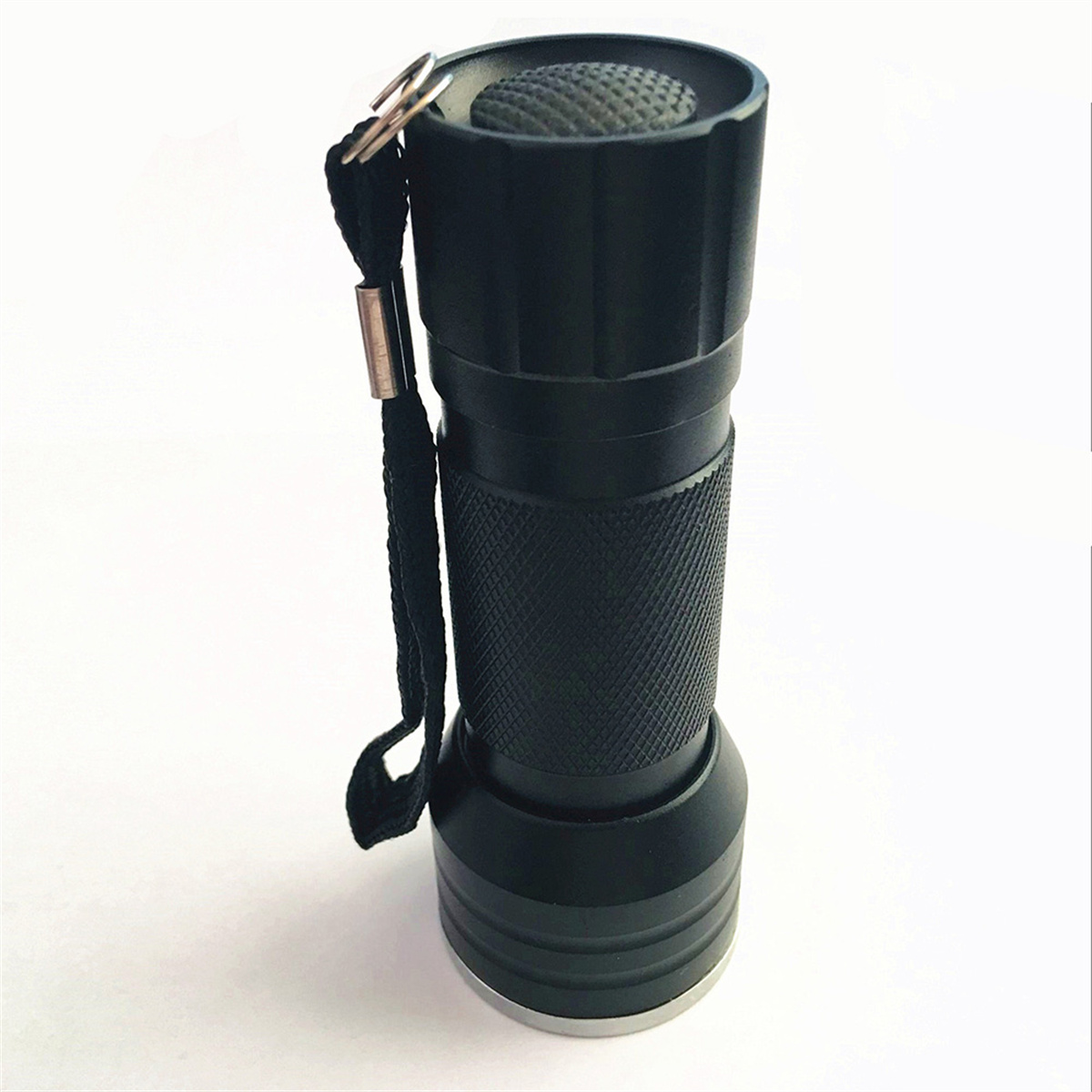 Eine kleine schwarze Taschenlampe mit Handschlaufe, vor weißem Hintergrund.