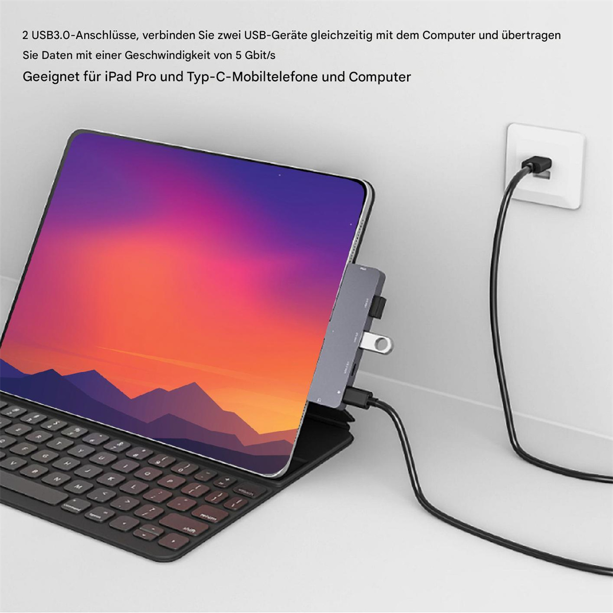 Laptop mit Tastatur und Hub. Der Hub ist an eine Steckdose angeschlossen.