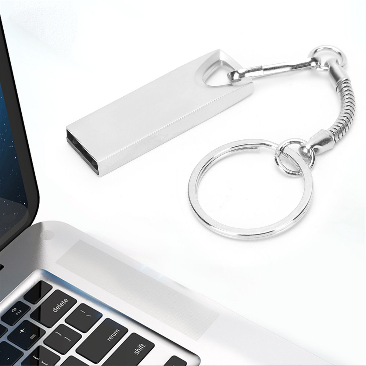 Ein silberner USB-Stick mit Schlüsselanhänger und einem Laptop. Der Stick ist rechteckig. Der Laptop ist geöffnet.