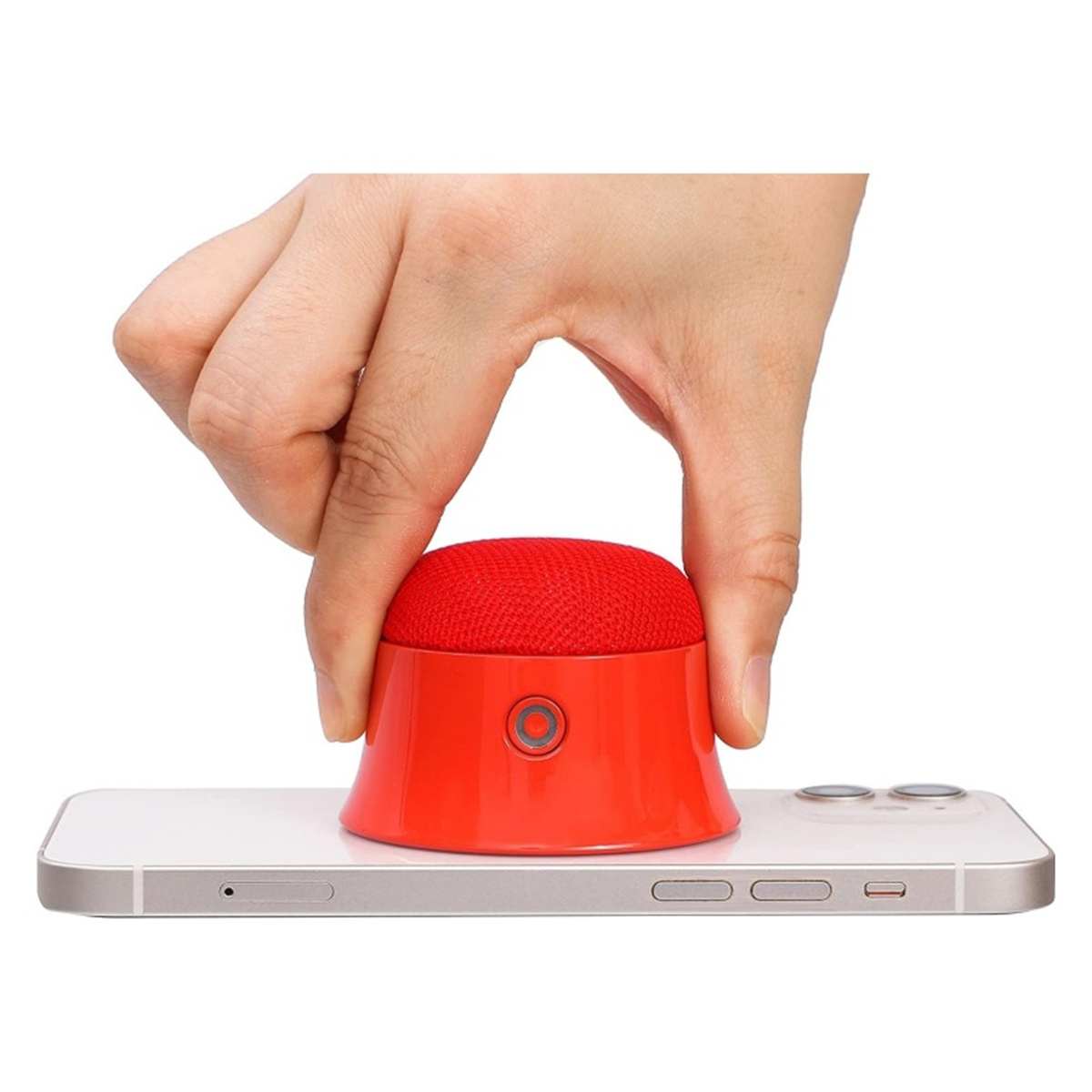 Eine Hand hält einen roten Lautsprecher über einem weißen Telefon. Der Lautsprecher ist rund und hat einen Knopf.