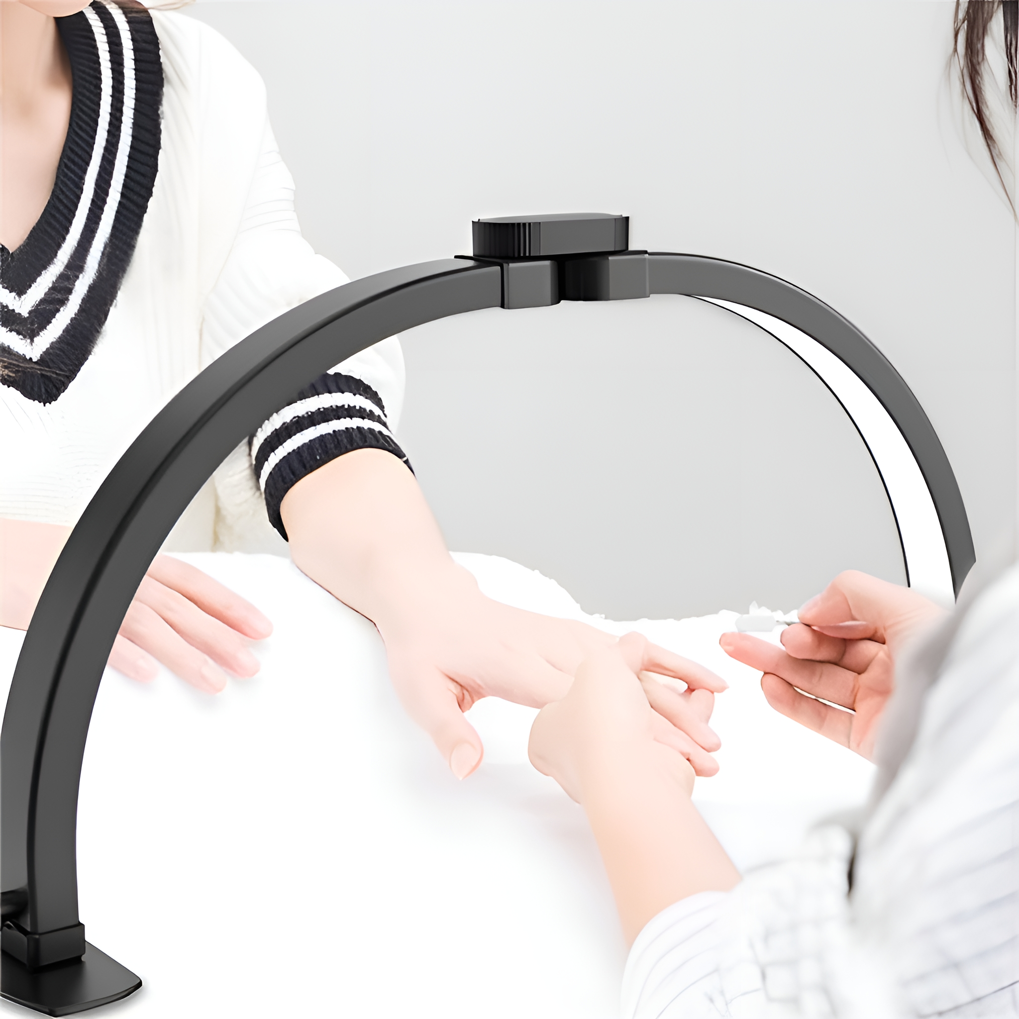 Eine Nageldesignerin arbeitet an den Nägeln einer Person unter einer schwarzen Bogenlampe.