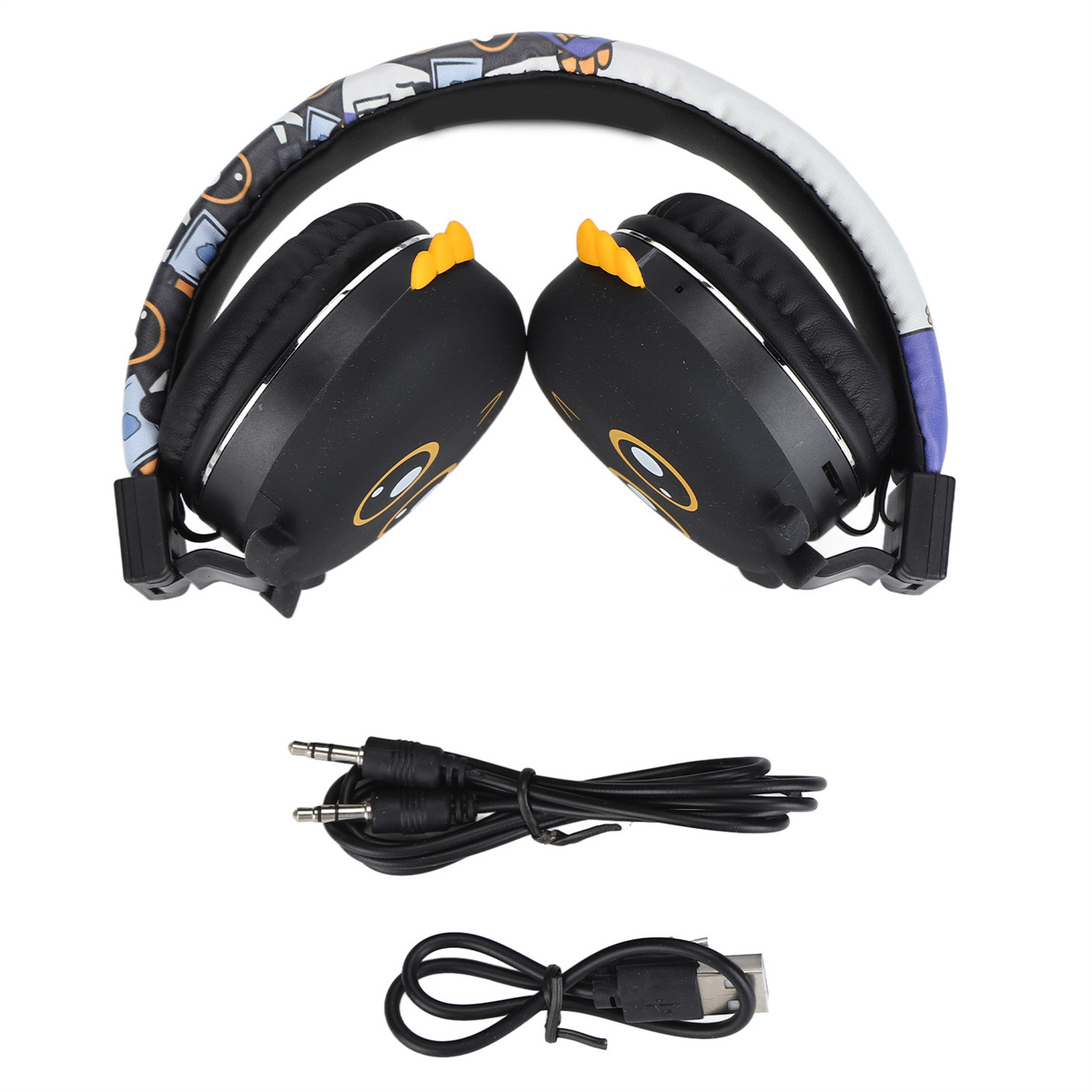 Schwarze Kopfhörer mit Cartoon-Designs, ein Ladekabel und ein 3,5-mm-Audiokabel auf weißem Untergrund.