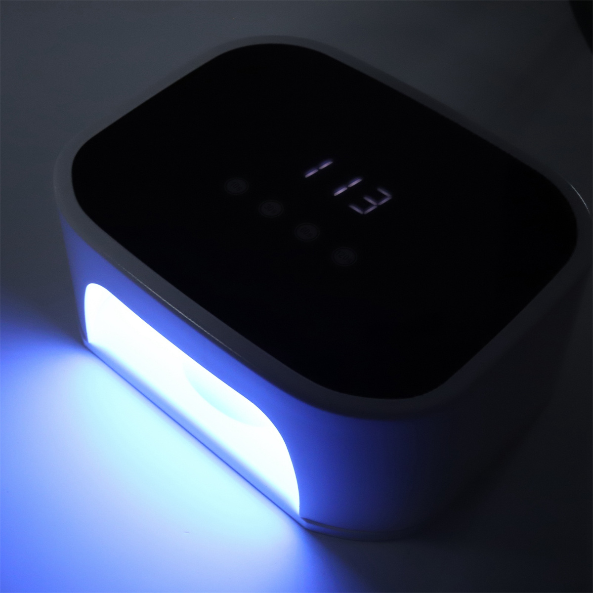 Eine weiß-schwarze Nagellampe. Anzeige zeigt 13. Die Lampe emittiert blaues Licht.