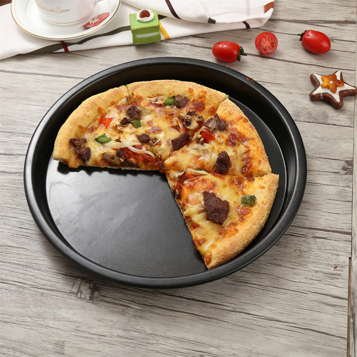 Eine Pizza auf einer schwarzen Pizzapfanne. Die Pizza ist geschnitten und belegt. Ein Stück fehlt.