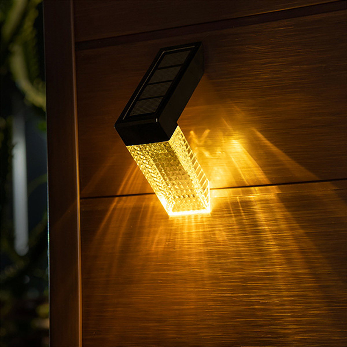 Eine solarbetriebene Leuchte ist auf einer Holzoberfläche montiert. Das Licht ist an und wirft ein helles Leuchten.