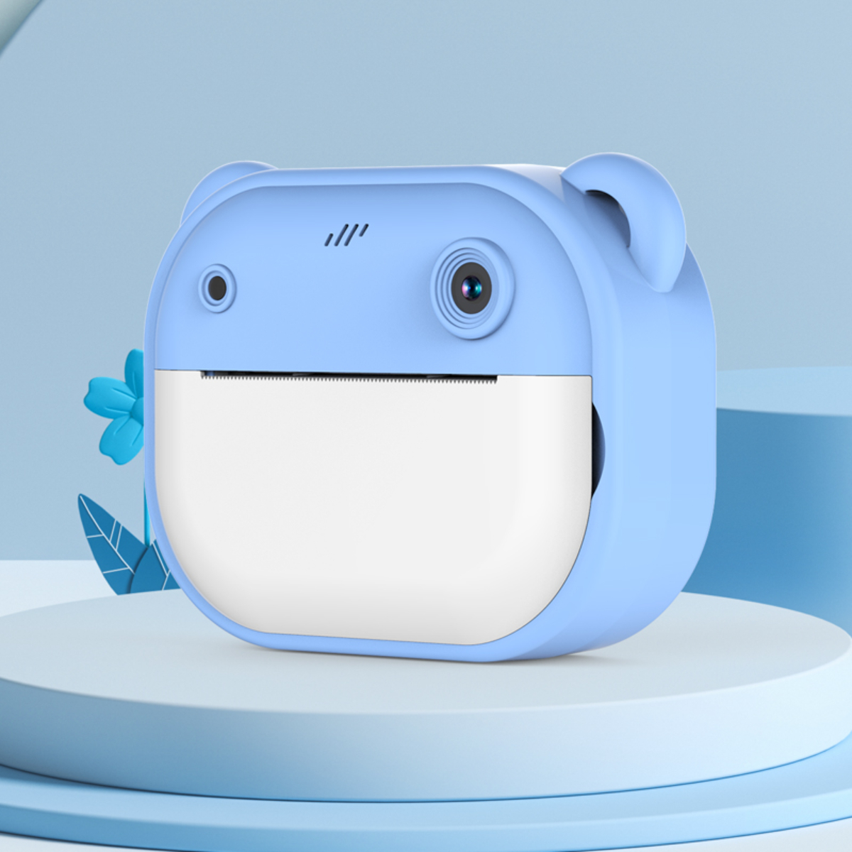 Blaue Kamera in Bärenform mit weißem Papierausgang. Sie steht auf einem weißen Ständer.