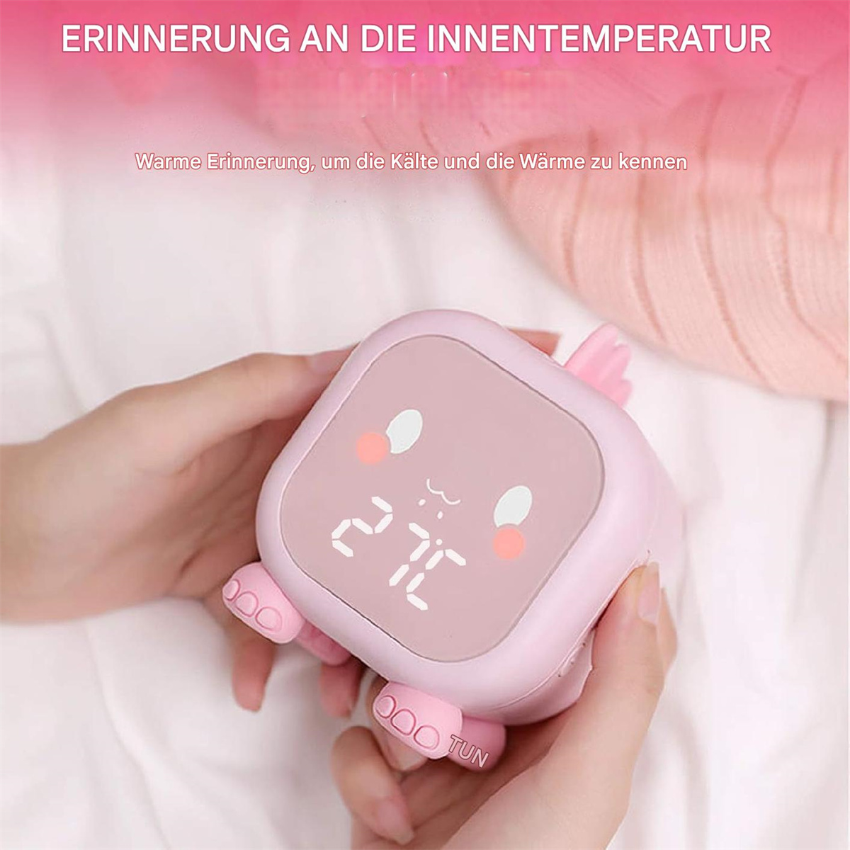 Ein pinkfarbener digitaler Wecker in Hasenform wird in Händen gehalten, mit weißem Hintergrund.