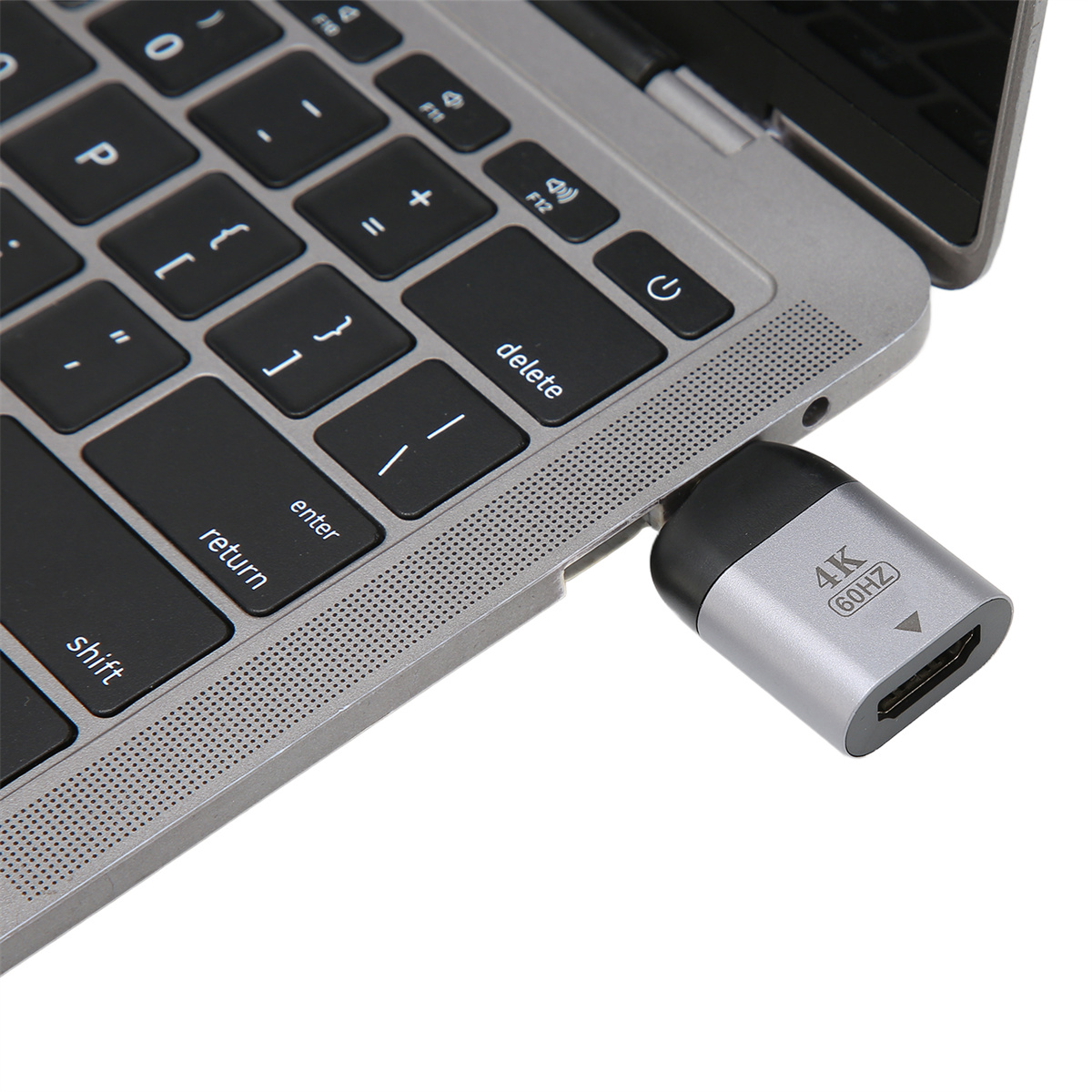Laptop-Tastatur mit einem silbernen Adapter, der eingesteckt ist. Der Adapter hat eine schwarze Kappe und einen HDMI-Anschluss.