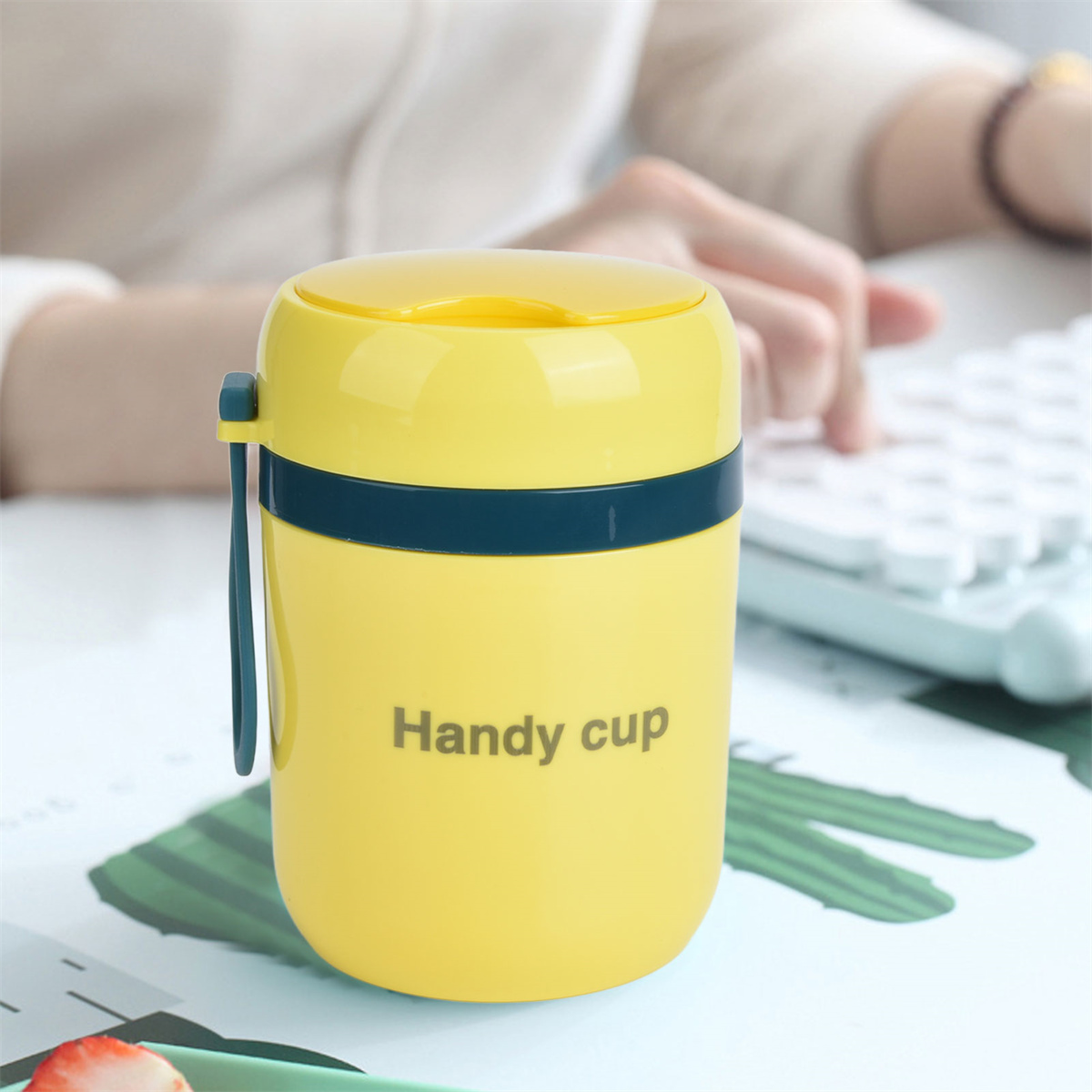 Gelber Isolierbecher mit gelbem Deckel und dunkelblauem Band. Text: 'Handy cup'.