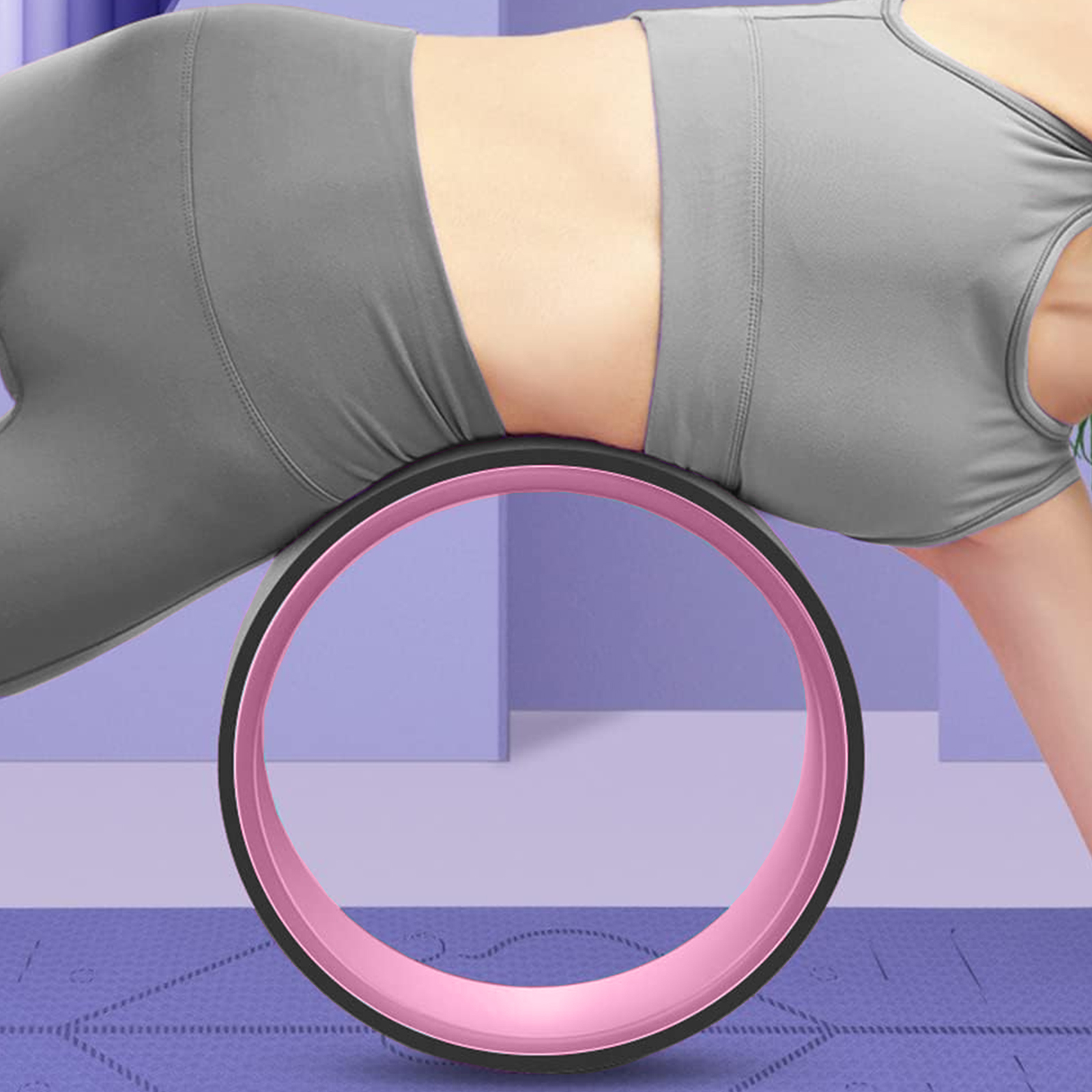 Una mujer hace ejercicio con una rueda de yoga rosa, sobre una esterilla morada, en una habitación lila.