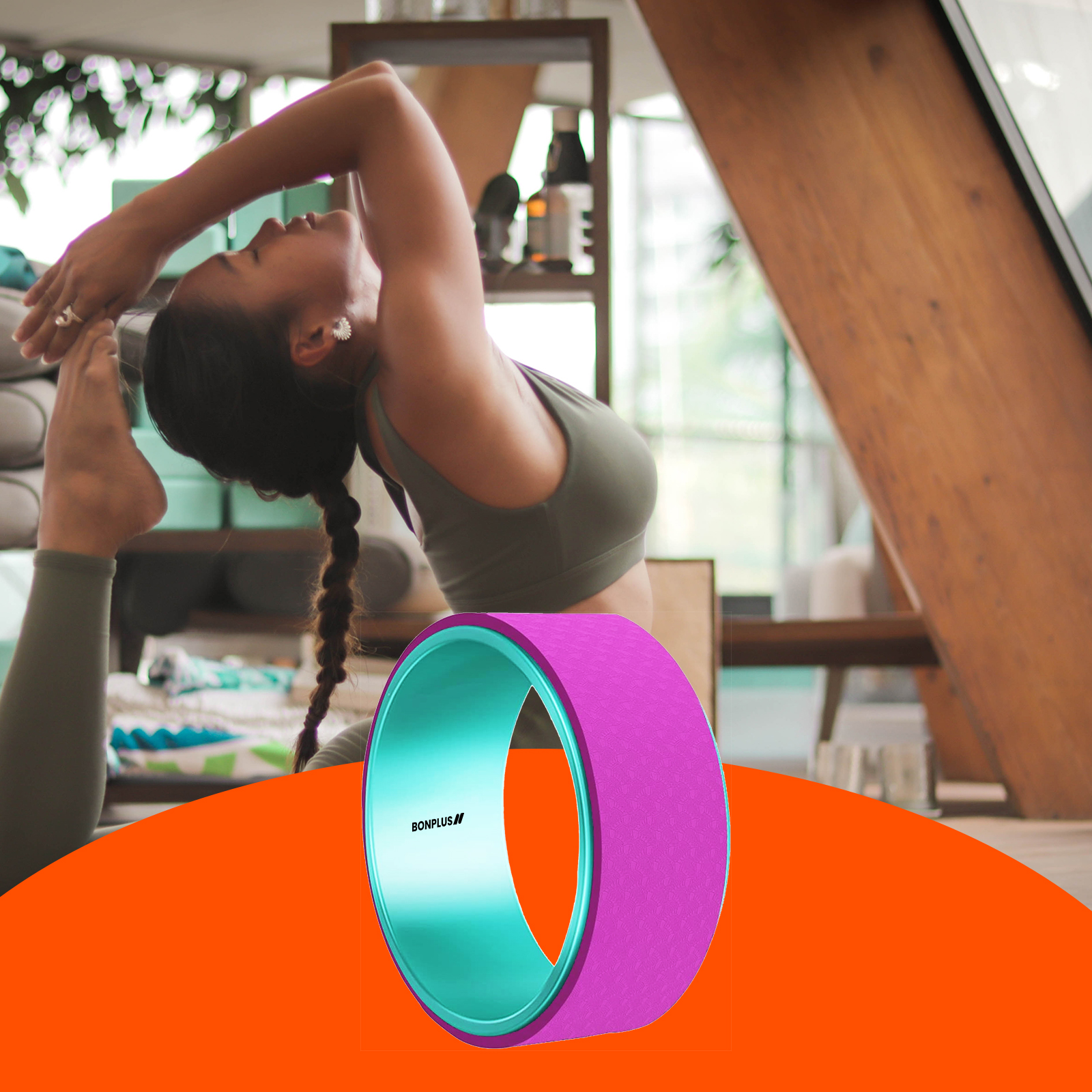 Mujer en pose de yoga con una rueda de yoga morada y turquesa en primer plano, fondo naranja.