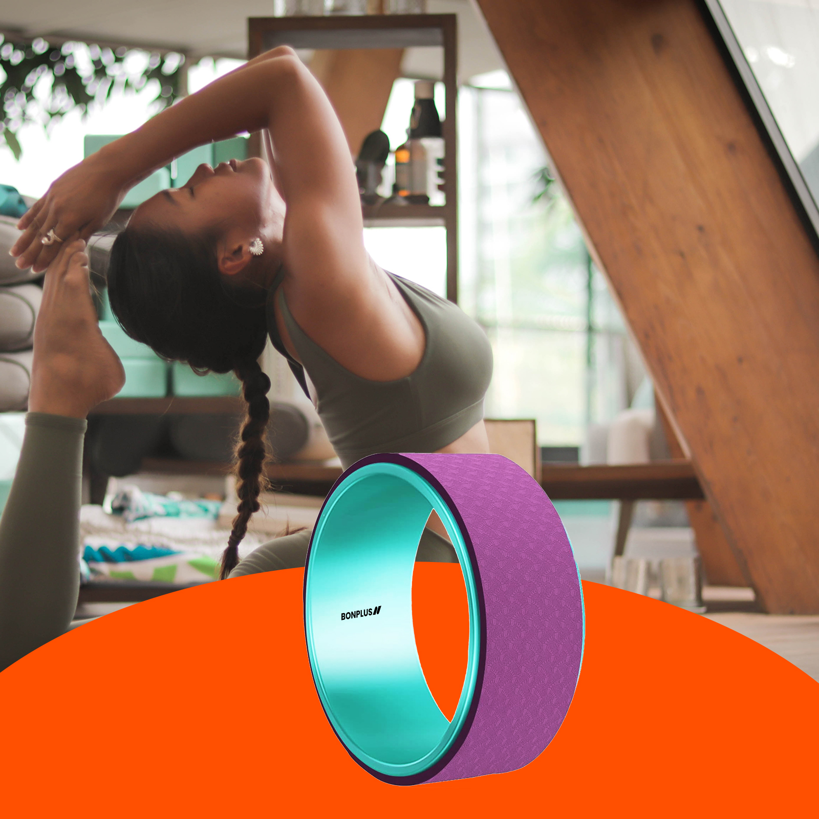 Mujer haciendo yoga con una rueda morada y turquesa. Fondo: habitación y plantas.