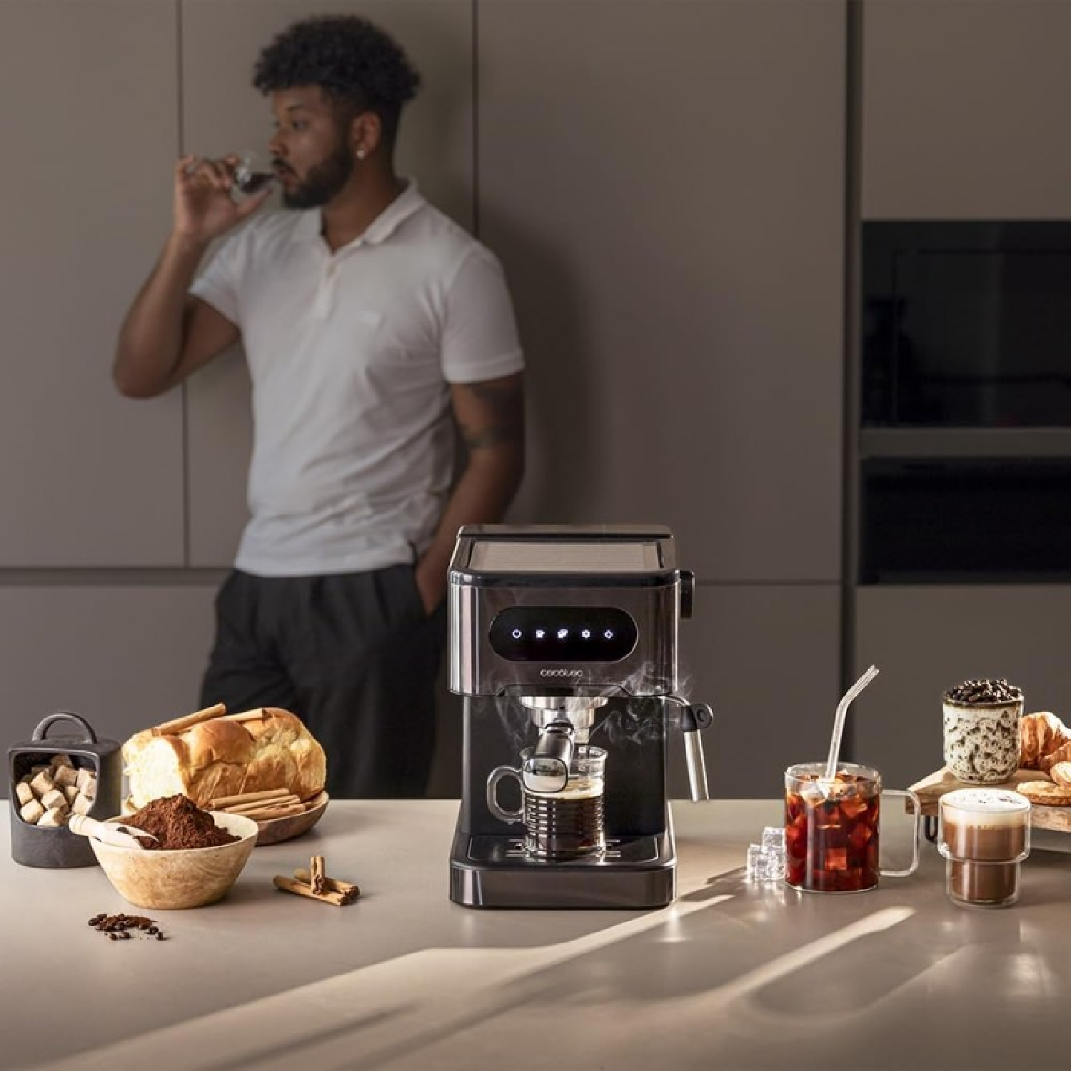 Mężczyzna robi kawę ekspresem do espresso. Filiżanki i składniki kawy są na stole.