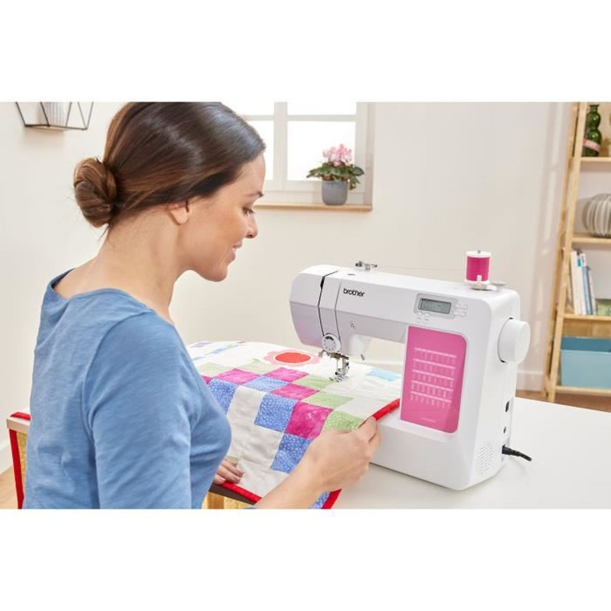 Eine Frau näht eine Steppdecke mit einer weißen Nähmaschine. Die Maschine hat ein rosa Detail.