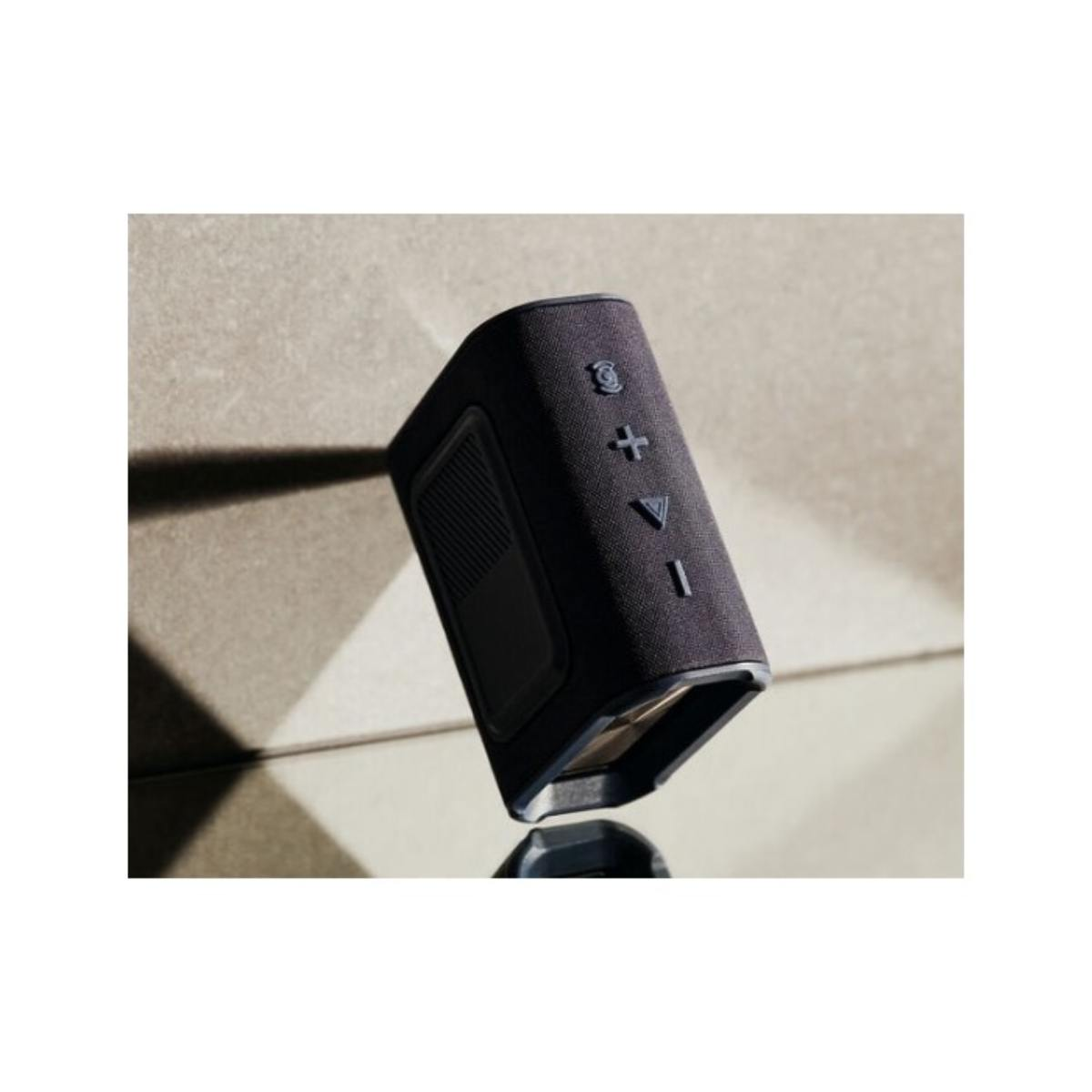 Un haut-parleur noir et rectangulaire incliné sur une surface réfléchissante.