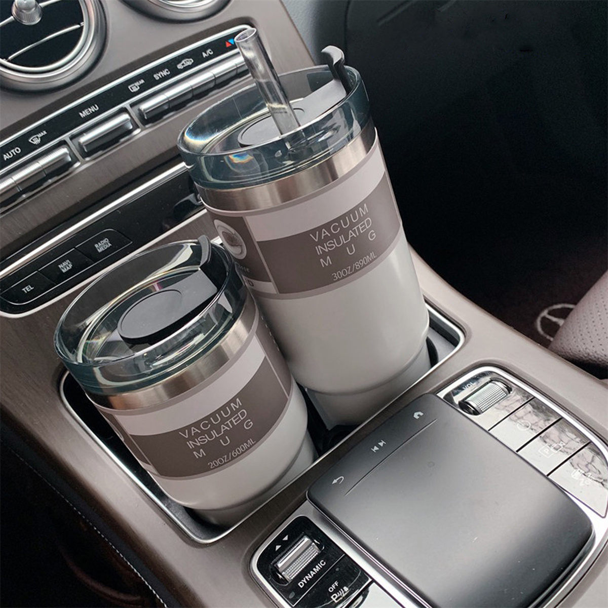Zwei isolierte Becher in einem Getränkehalter im Auto, mit Innenraum.