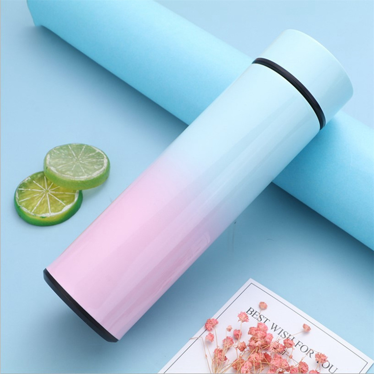 Ein blauer und rosa Thermosbehälter mit Zitronenscheiben und Blumen auf blauem Grund.