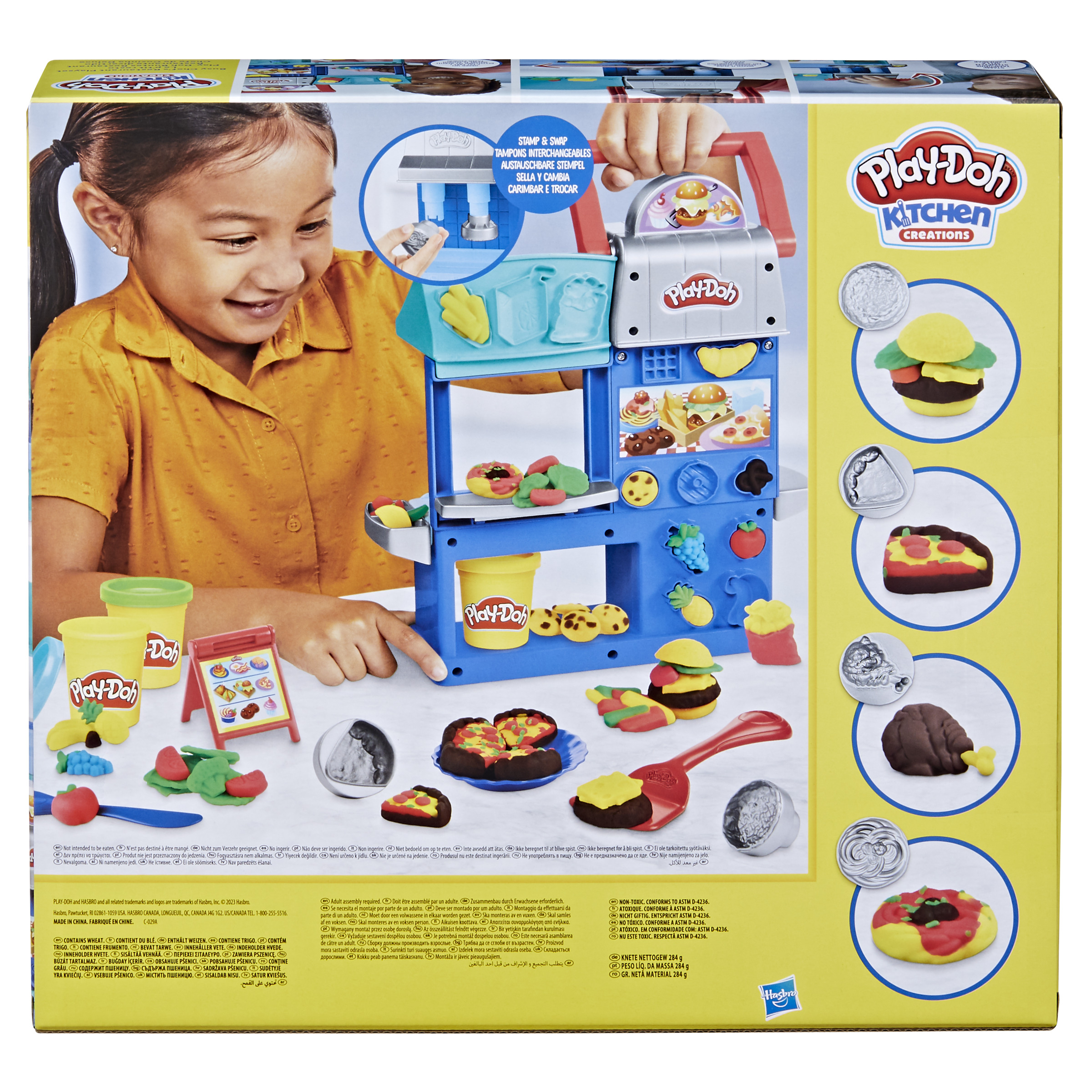 Un bambino indica una scatola Play-Doh Kitchen Creations con varie creazioni di cibo e strumenti Play-Doh.