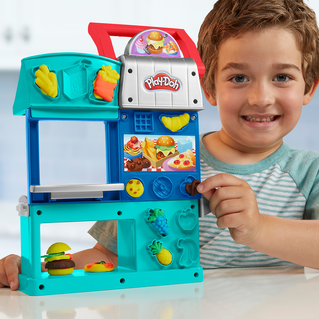 Un ragazzino gioca con un set di gioco Play-Doh. Ci sono stampi alimentari colorati.