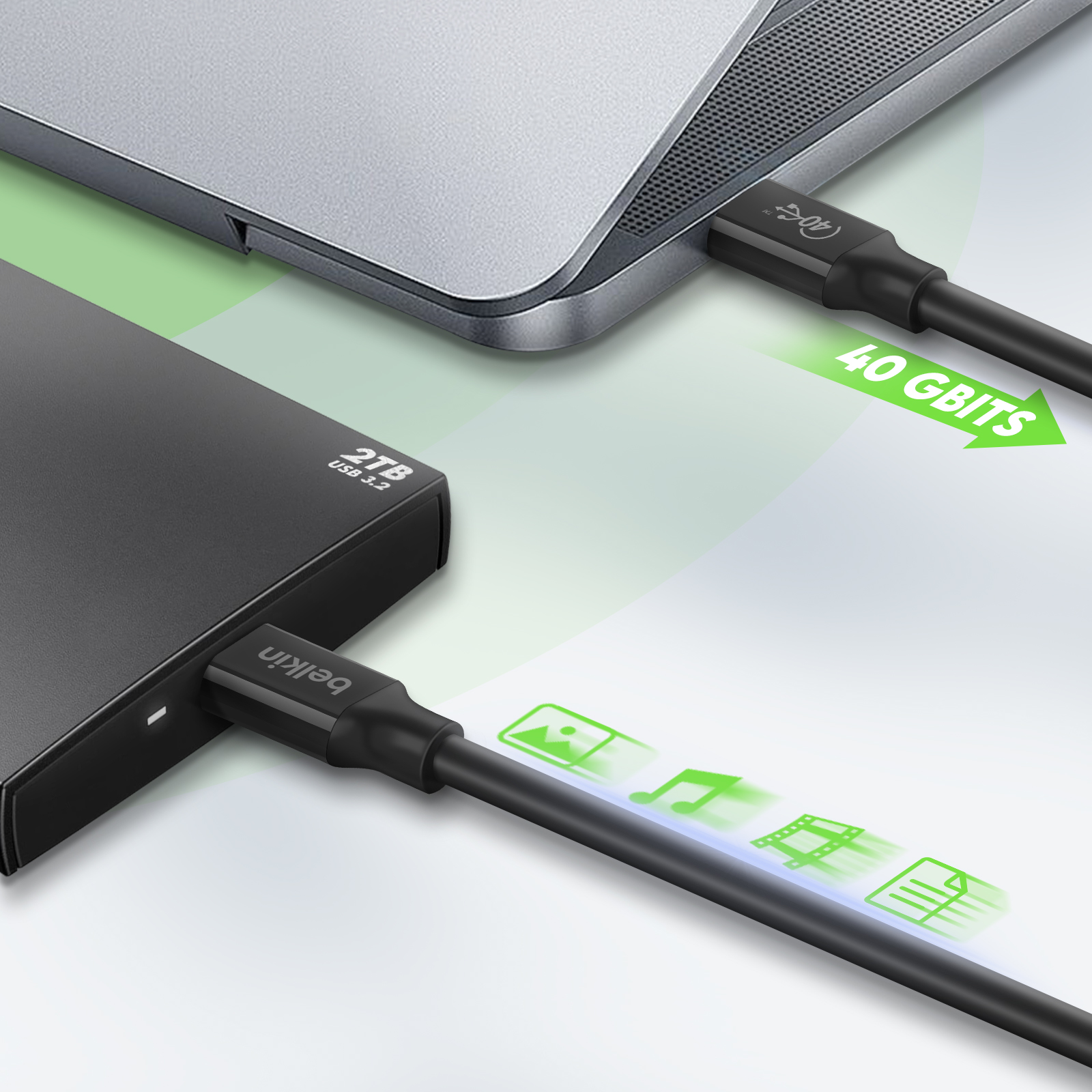 Laptop aangesloten op een zwarte externe harde schijf via een zwarte USB-kabel. Witte achtergrond.