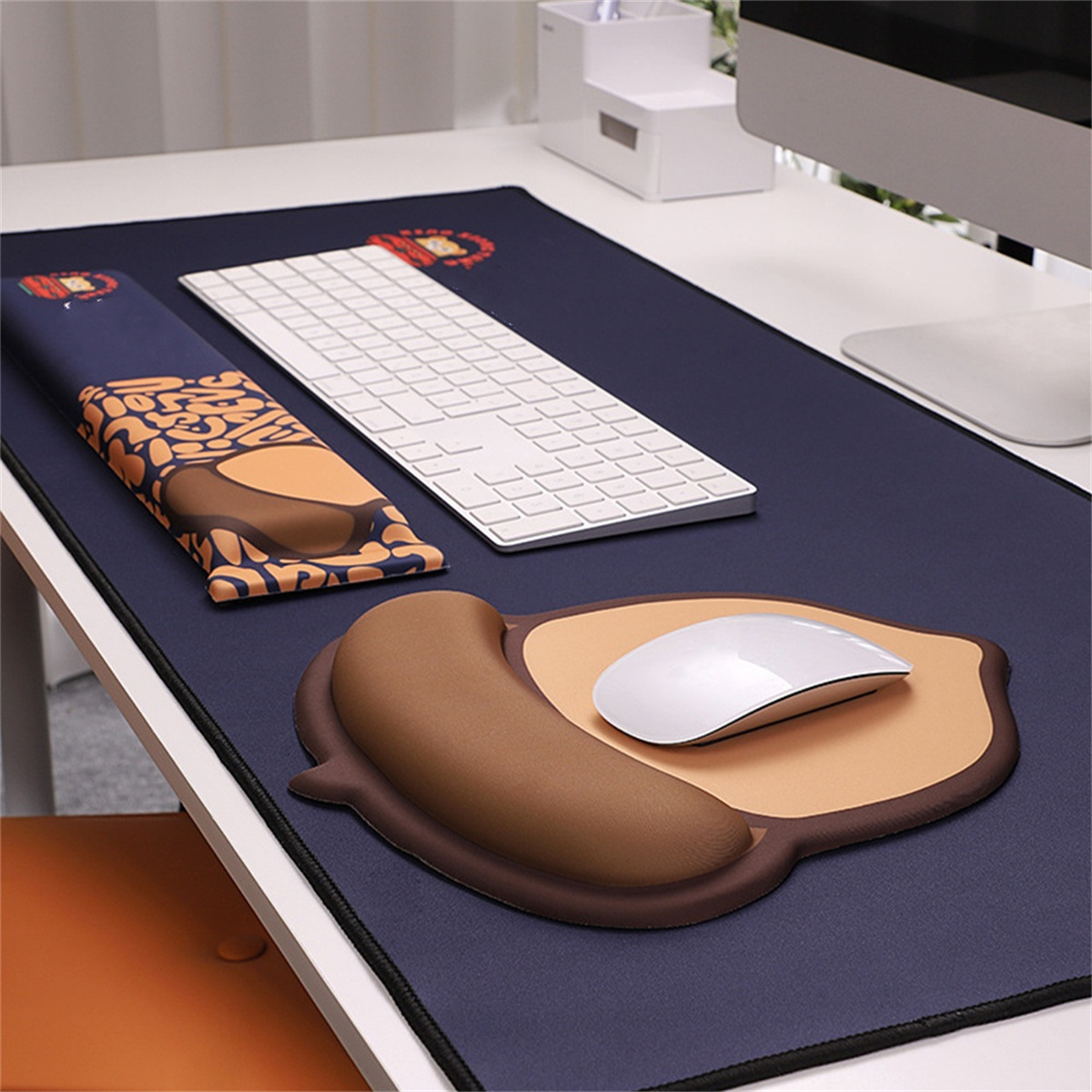 Mauspad mit Handgelenkauflage und Maus. Weiße Tastatur und Monitor im Hintergrund.