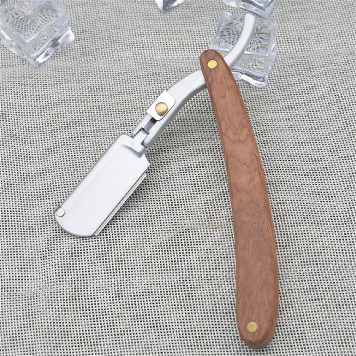 Ein Rasiermesser mit Holzgriff, offen und einsatzbereit. Die Klinge ist silberfarben.