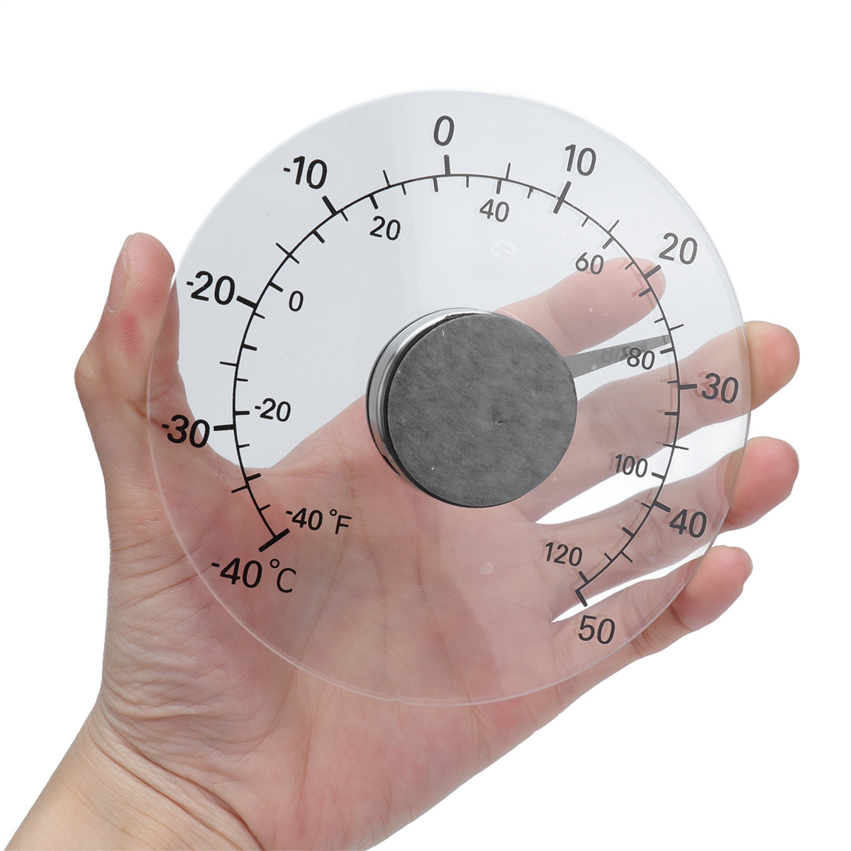 Ein klarer, runder Thermometer in einer Hand gehalten. Zeigt Temperaturmesswerte an. Zahlen und Markierungen sind sichtbar.