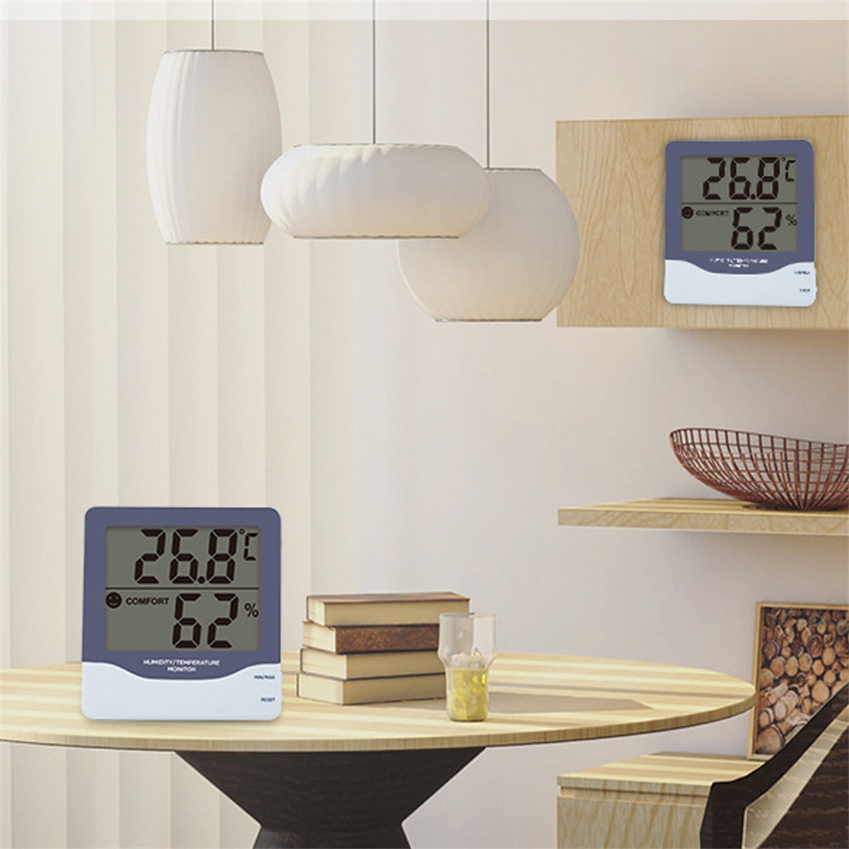 Zwei digitale Thermometer auf einem Tisch. Eines rechts, eines links. Hintergrund: Lampen.