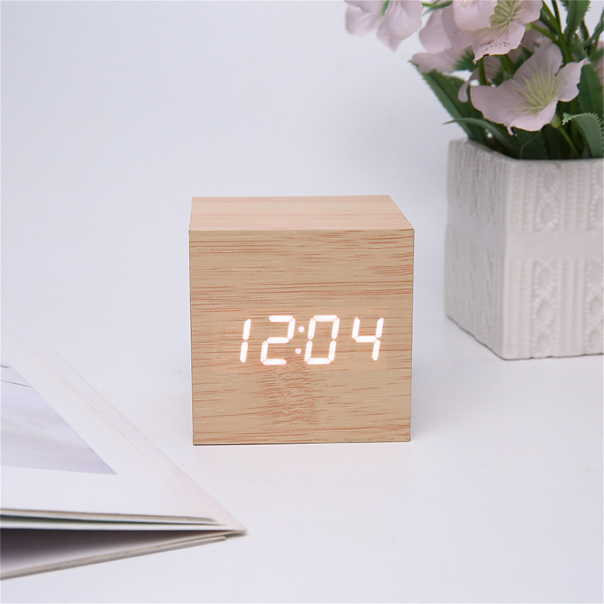 Würfeluhr aus Holz, die 12:04 anzeigt. Weiße Ziffern auf hellem Holzgrund. Weißer Hintergrund.