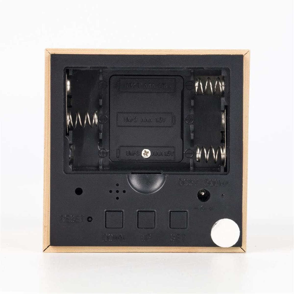 Die Rückseite einer hölzernen quadratischen Digitaluhr mit Batteriefächern und Knöpfen.