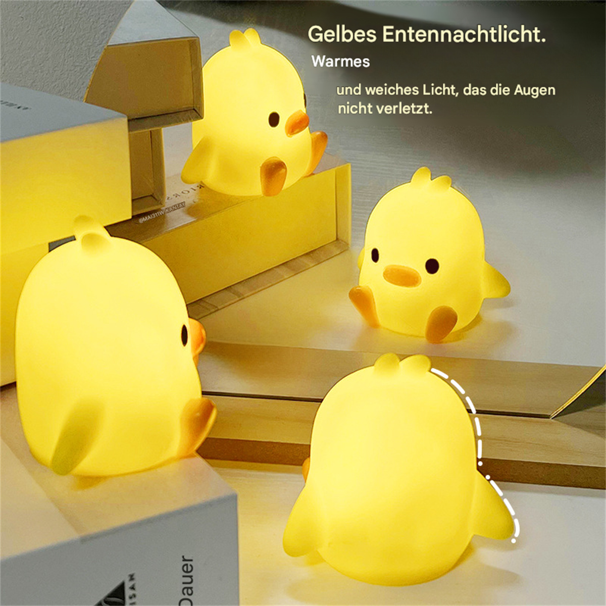 Vier gelbe, kükenförmige Nachtlichter auf einer Oberfläche. Licht scheint von ihnen aus. Kisten sind im Hintergrund.