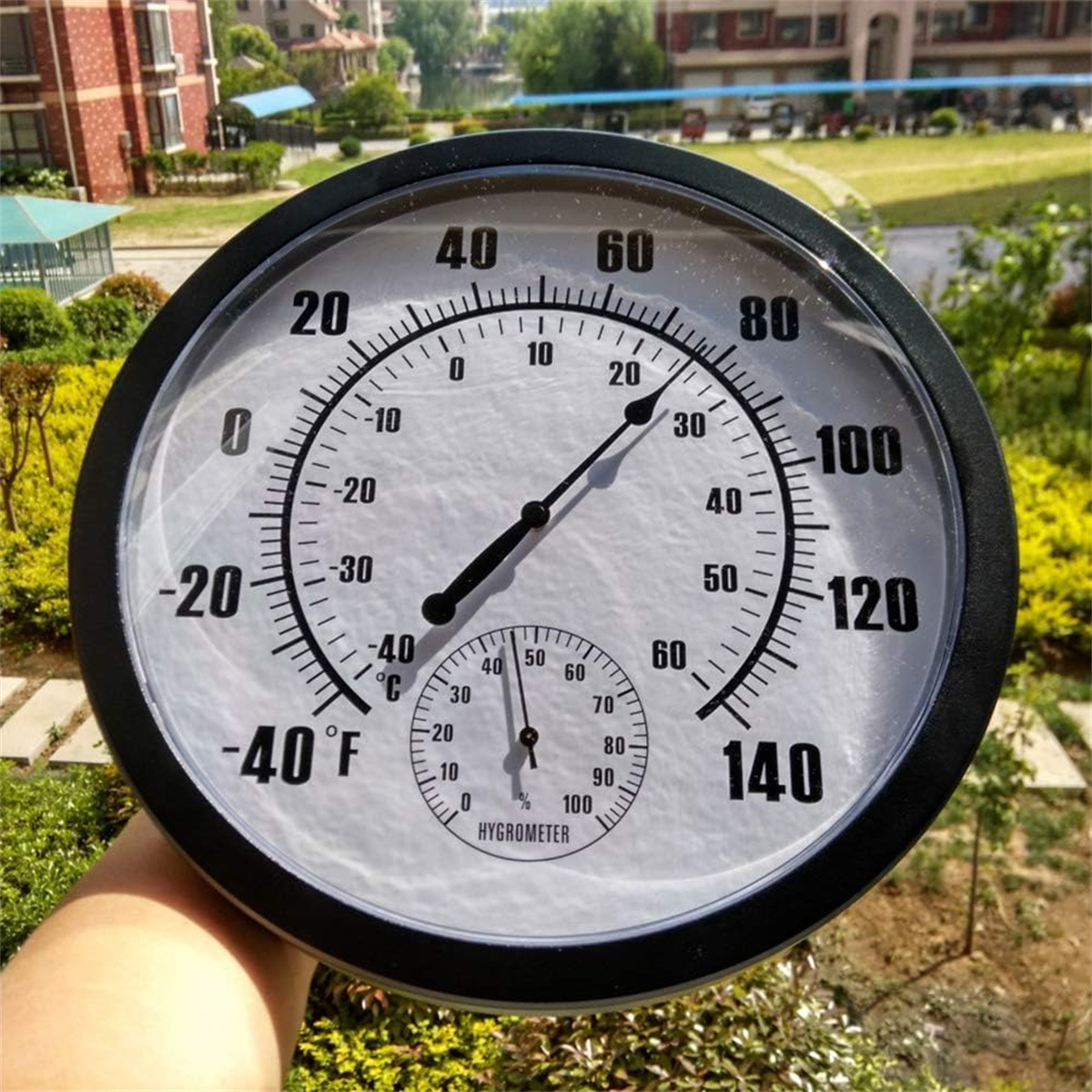Ein schwarz-weißes rundes Thermometer mit einem kleineren Hygrometer. Die Temperatur beträgt etwa 20 Grad.