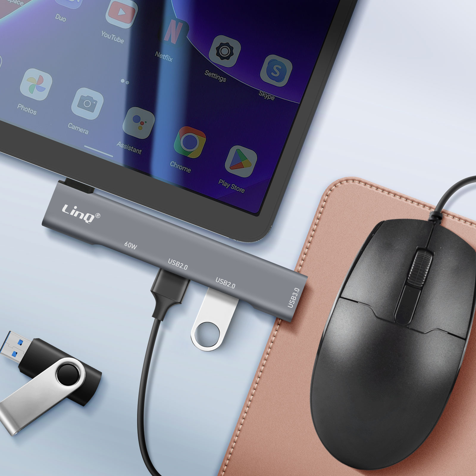 Une tablette connectée à un hub et un lecteur USB, avec une souris et un tapis de souris rose.