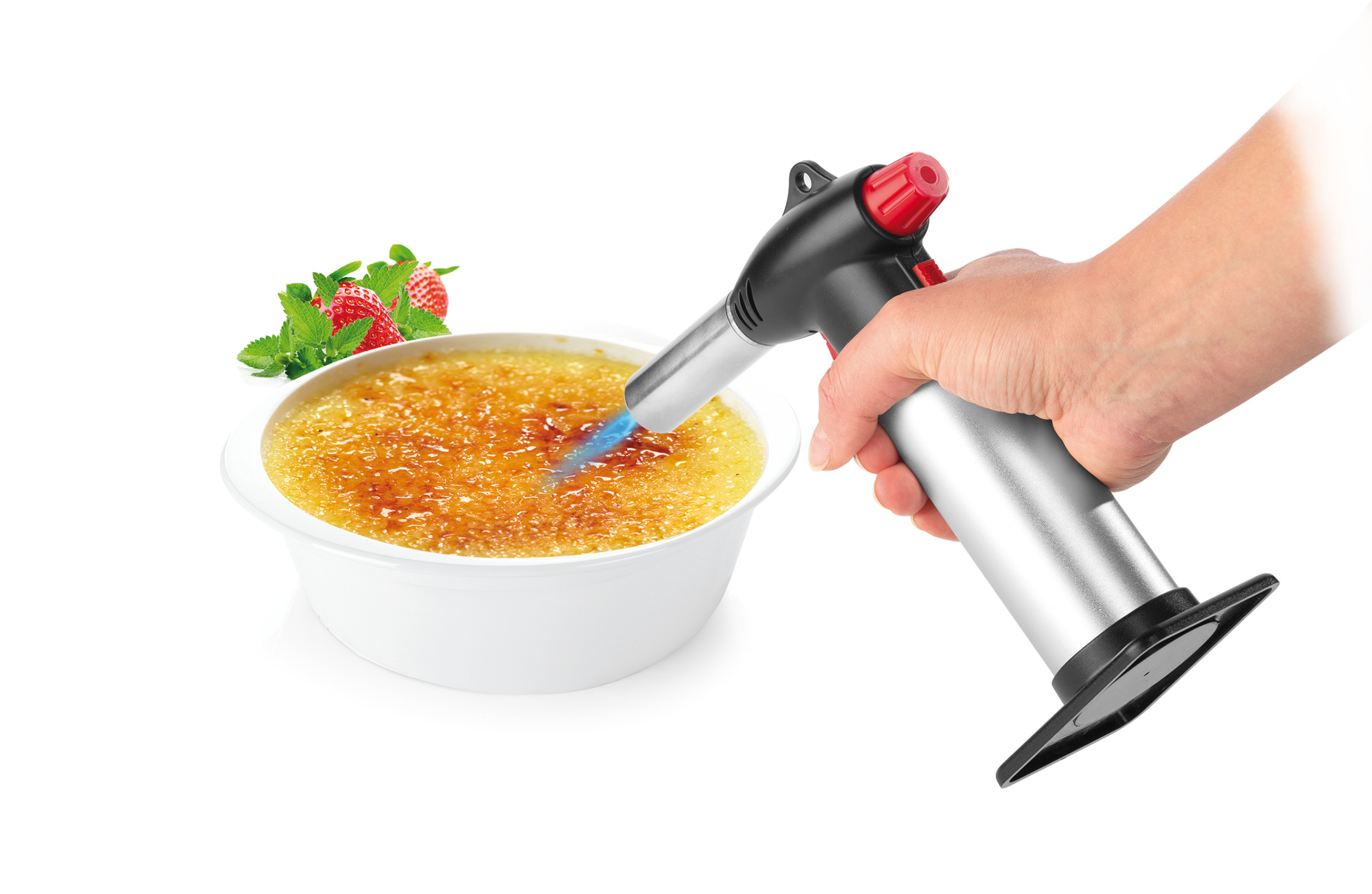 Eine Hand karamellisiert Crème brûlée mit einem Brenner in einer weißen Schüssel, weißer Hintergrund.