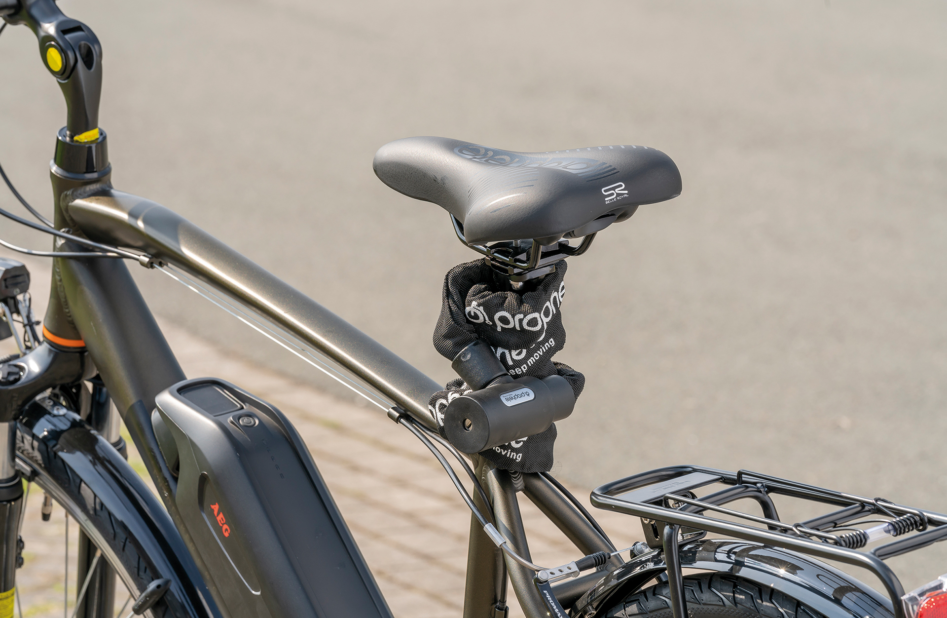 Elektrofahrrad mit schwarzem Sitz, Schloss und Akku, vor verschwommenem Hintergrund.