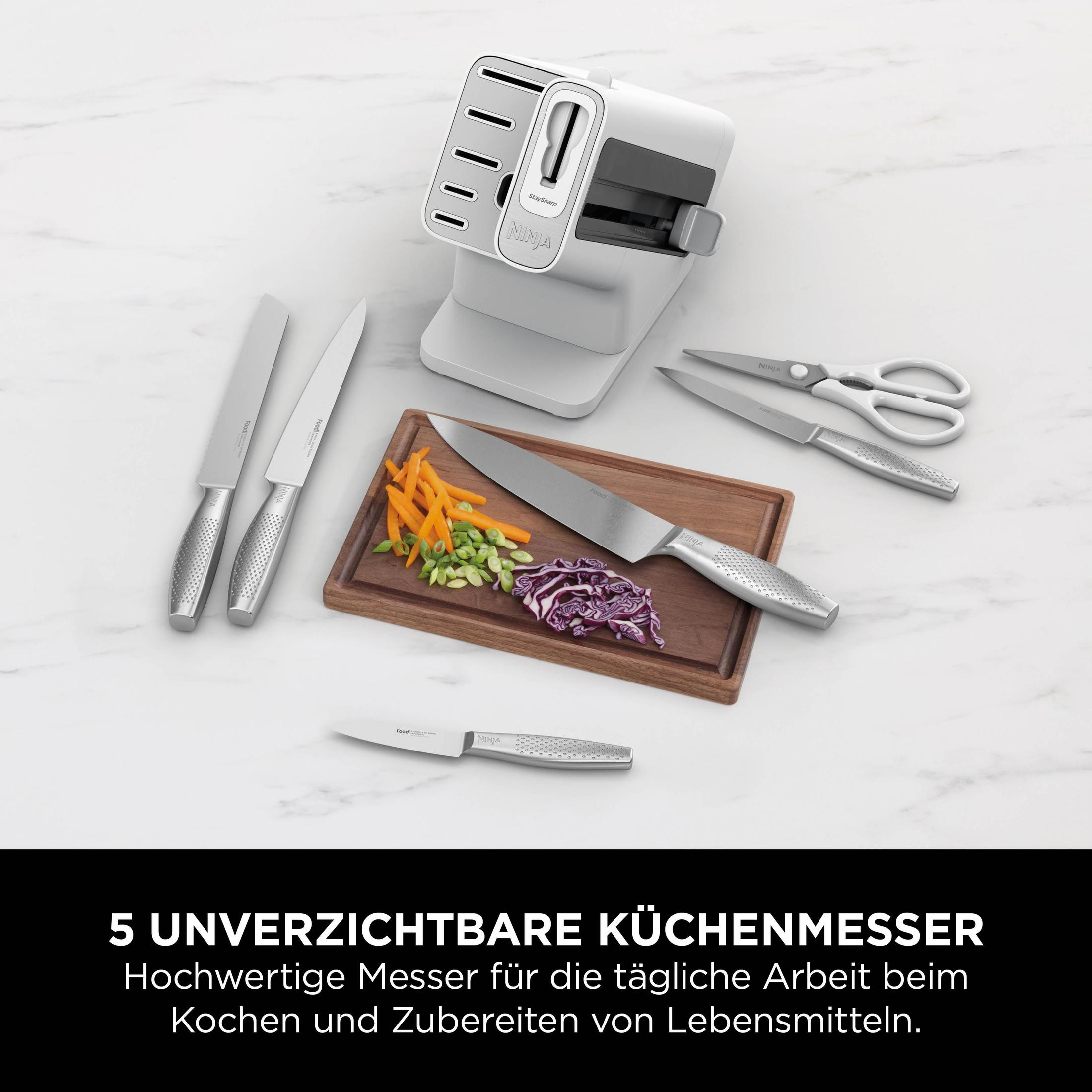 Messerset auf Marmor. Messer, Schneidebrett mit Gemüse, Messerschärfer. Marke Ninja, weiß.